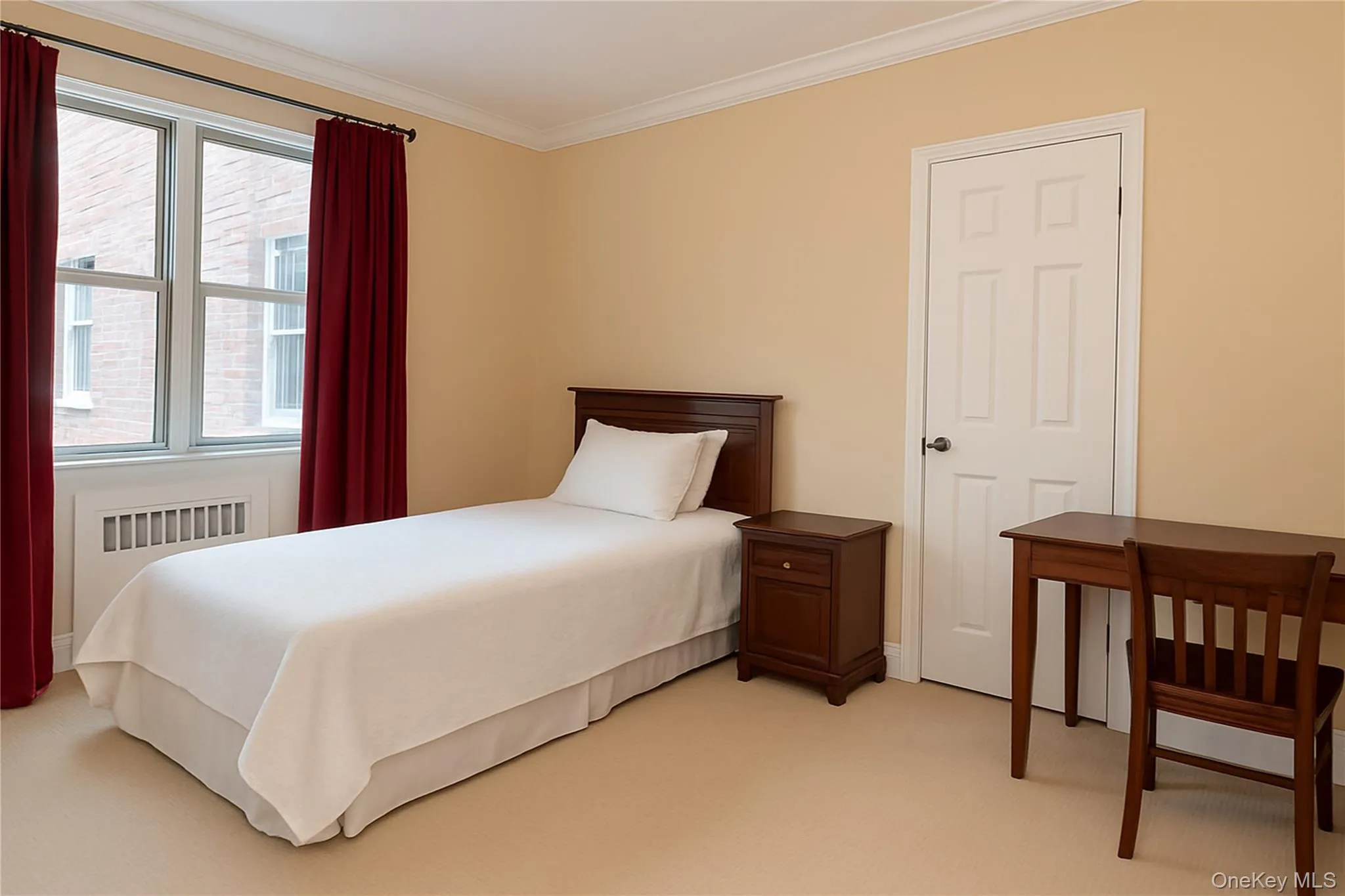 Bedroom with light colored carpet, radiator heating unit, and crown molding Bedroom with light colored carpet, radiator heating unit, and crown molding