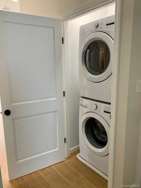 Laundry room featuring wood tiled floors and stacked washing machine and dryer Laundry room featuring wood tiled floors and stacked washing machine and dryer