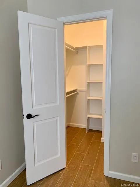 Walk in closet featuring wood finish floors Walk in closet featuring wood finish floors