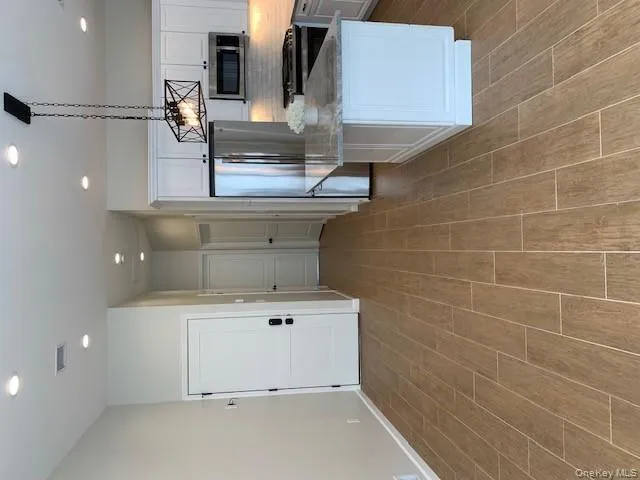Kitchen with white cabinets, backsplash, recessed lighting, fridge, and light stone countertops Kitchen with white cabinets, backsplash, recessed lighting, fridge, and light stone countertops