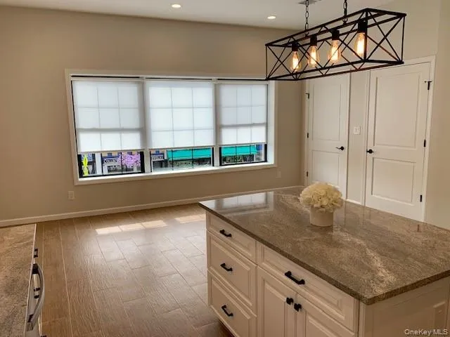 Kitchen with plenty of natural light, dark stone countertops, decorative light fixtures, light wood-type flooring, and recessed lighting Kitchen with plenty of natural light, dark stone countertops, decorative light fixtures, light wood-type flooring, and recessed lighting
