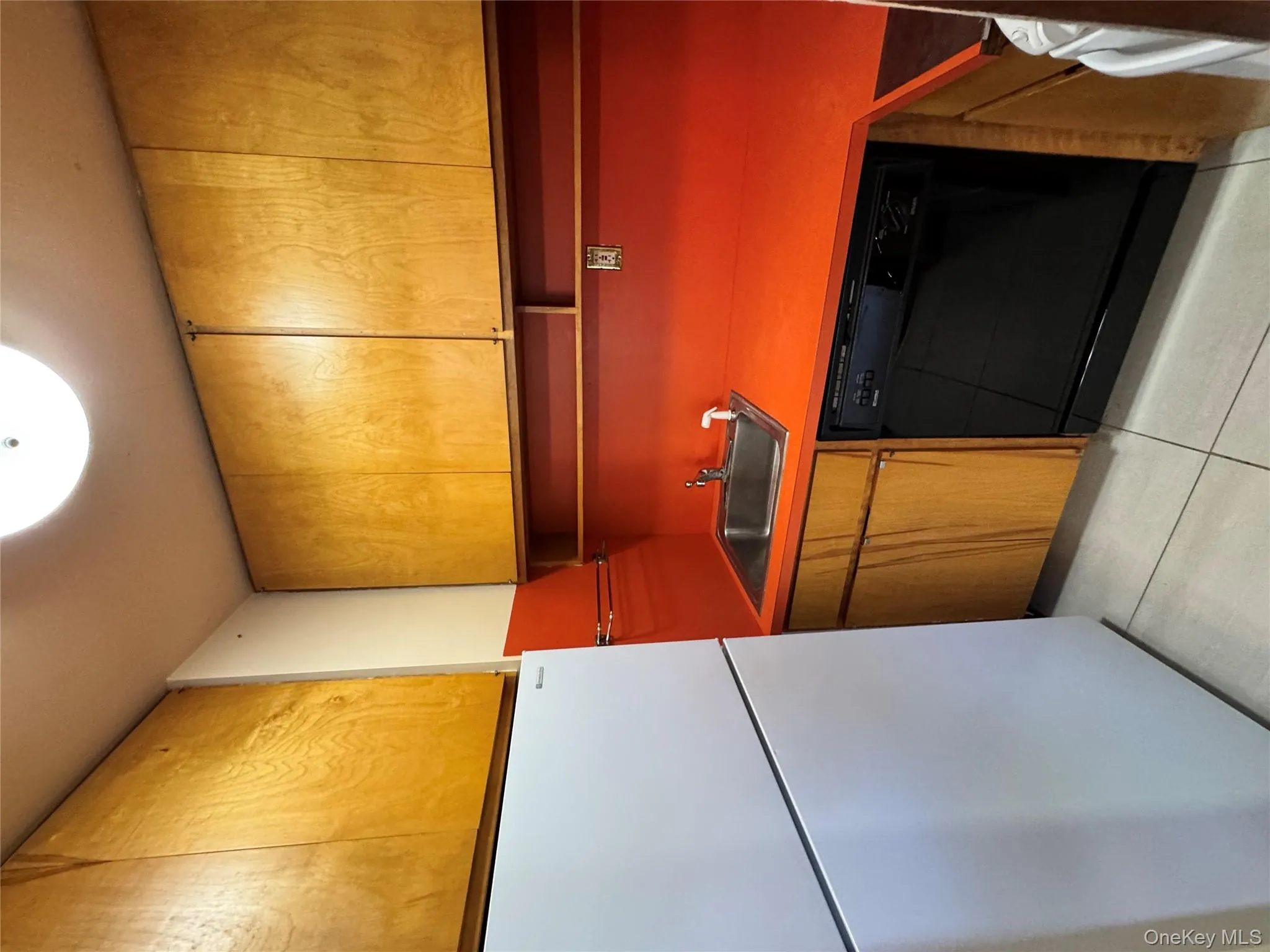 Kitchen with refrigerator, brown cabinetry, white dishwasher, light tile patterned floors, and wall oven Kitchen with refrigerator, brown cabinetry, white dishwasher, light tile patterned floors, and wall oven