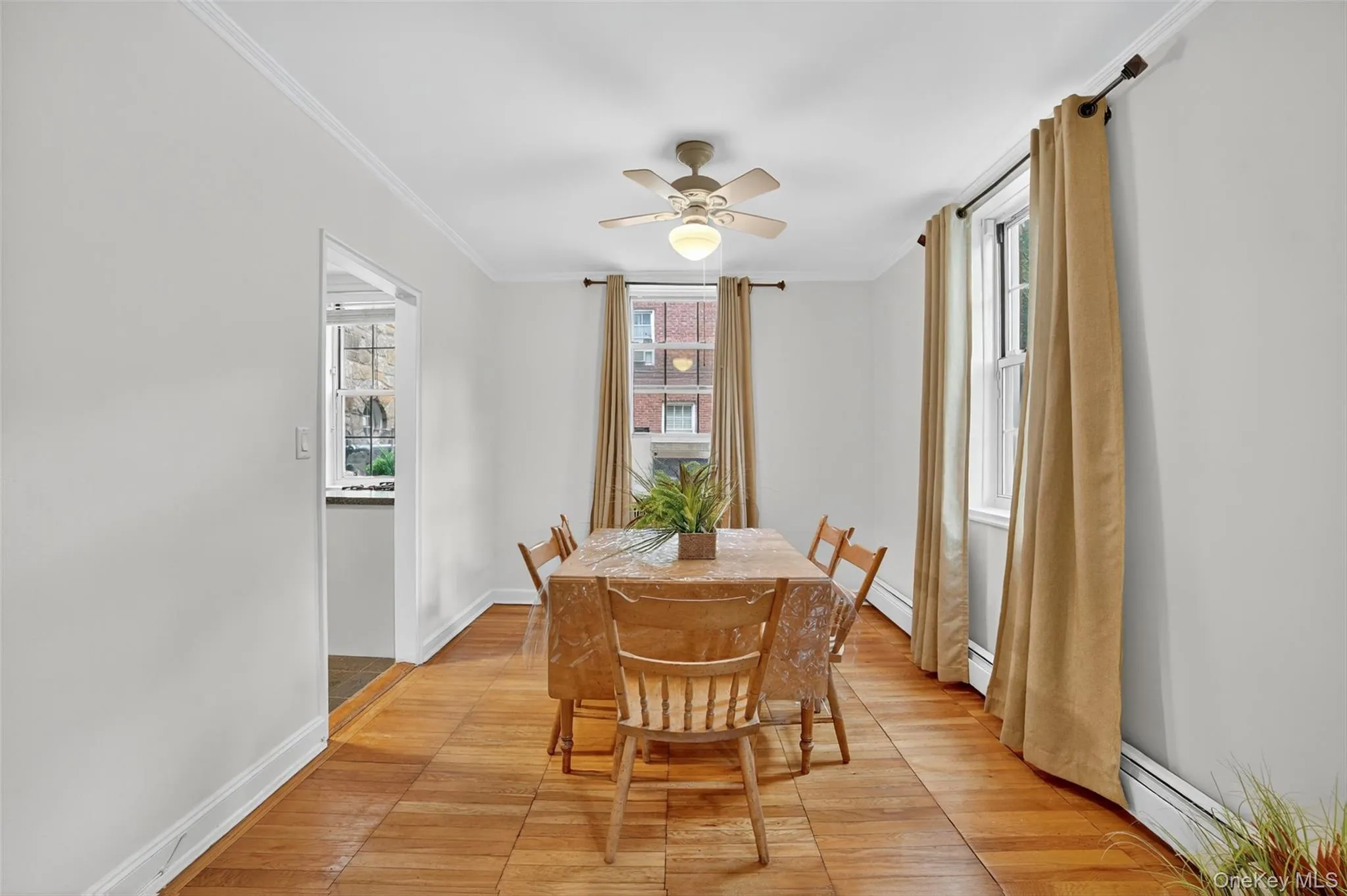 Dining area featuring ornamental molding, healthy amount of natural light, light wood-style flooring, ceiling fan, and a baseboard radiator Dining area featuring ornamental molding, healthy amount of natural light, light wood-style flooring, ceiling fan, and a baseboard radiator