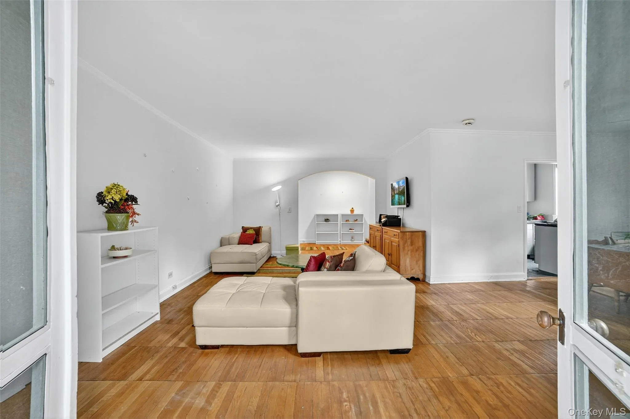 Living area featuring ornamental molding, wood finished floors, and arched walkways Living area featuring ornamental molding, wood finished floors, and arched walkways