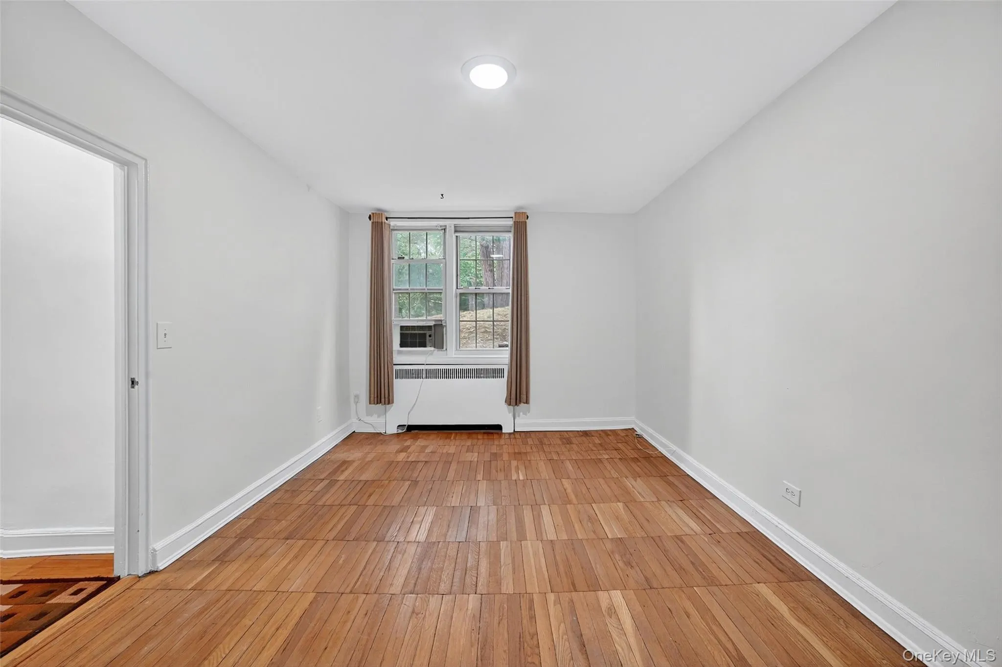 Empty room featuring light wood finished floors and radiator heating unit Empty room featuring light wood finished floors and radiator heating unit