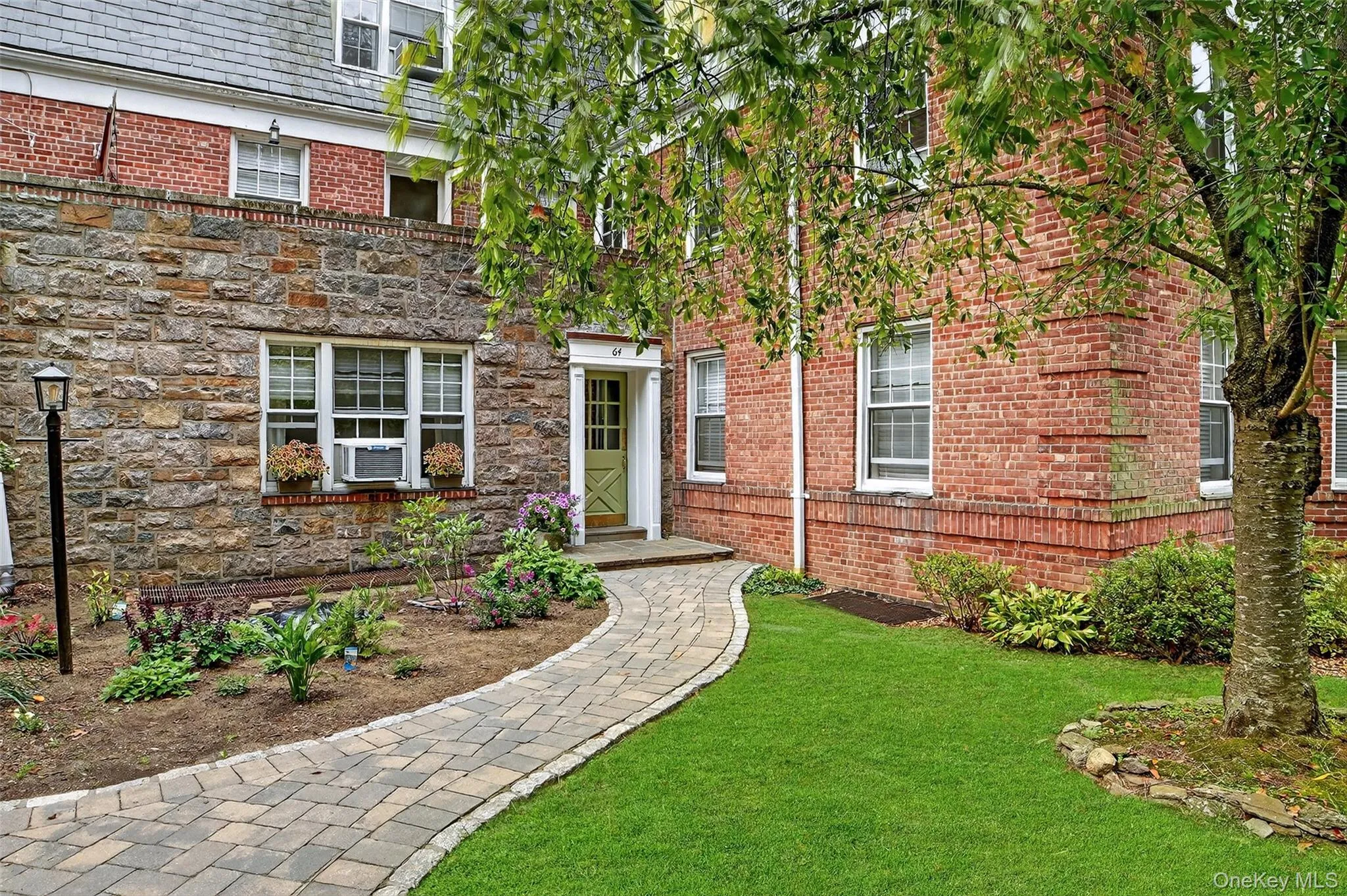 Doorway to property with a high end roof, a yard, and brick siding Doorway to property with a high end roof, a yard, and brick siding