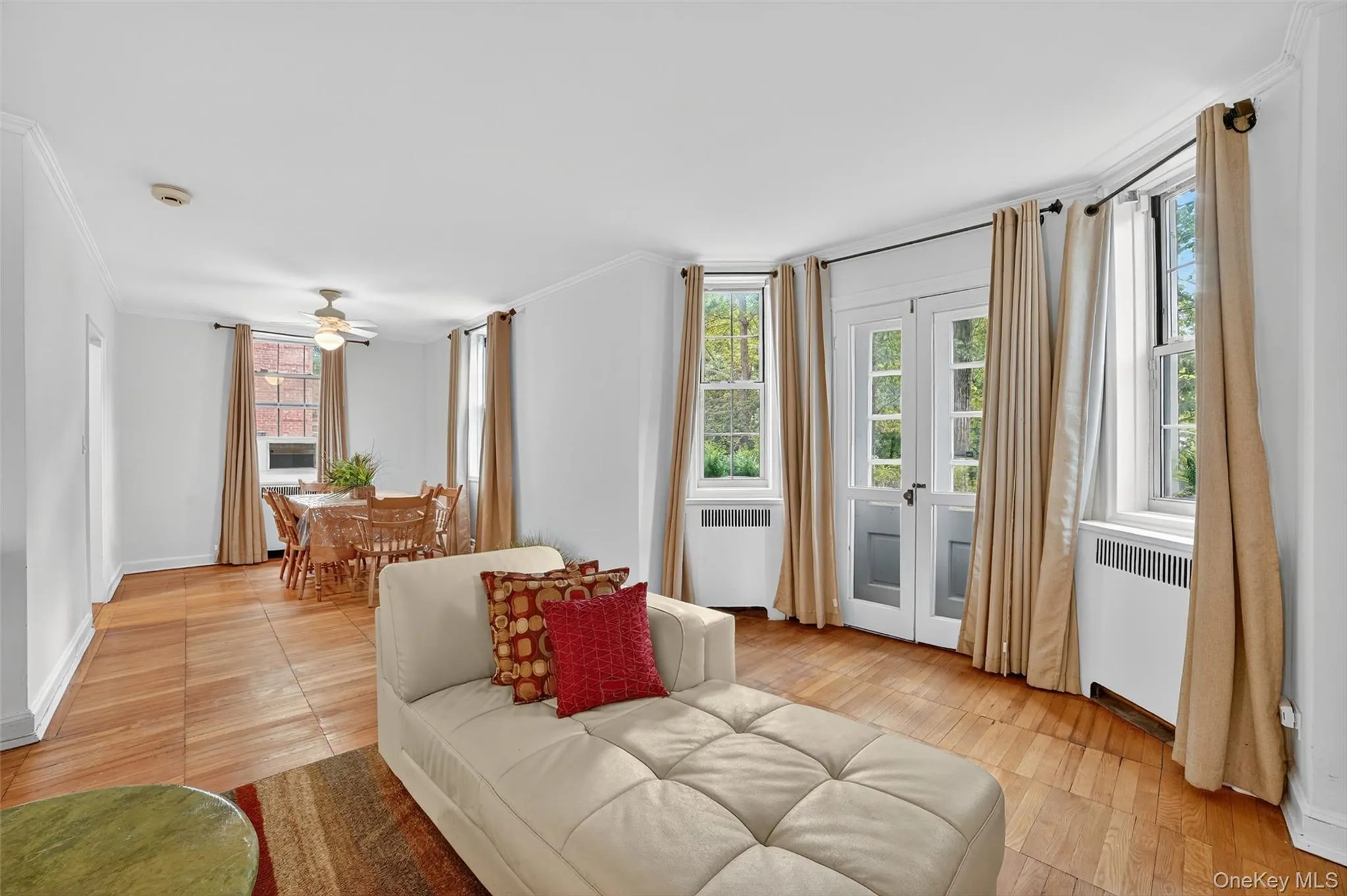 Living area featuring crown molding, radiator heating unit, and healthy amount of natural light Living area featuring crown molding, radiator heating unit, and healthy amount of natural light