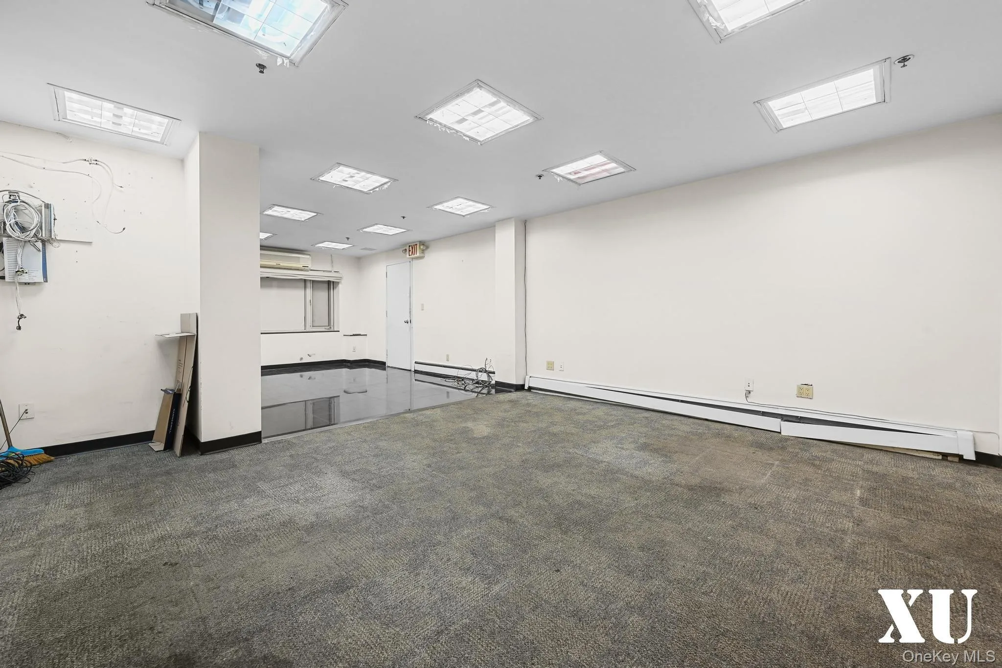 Empty room featuring baseboard heating and dark colored carpet Empty room featuring baseboard heating and dark colored carpet
