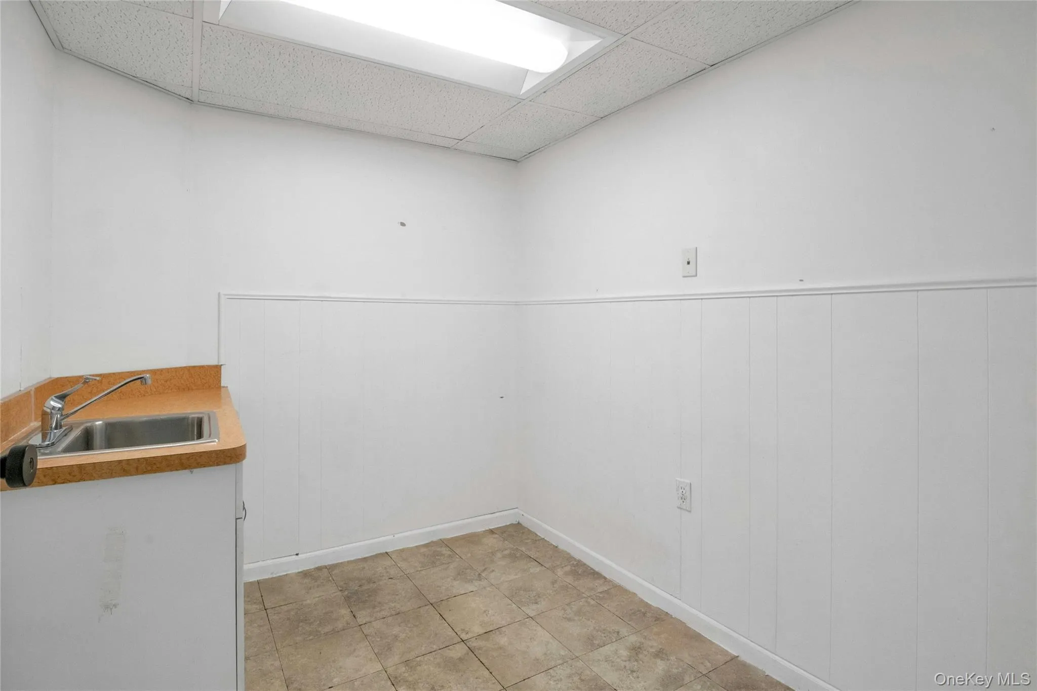 Laundry area with a wainscoted wall and light tile patterned floors Laundry area with a wainscoted wall and light tile patterned floors