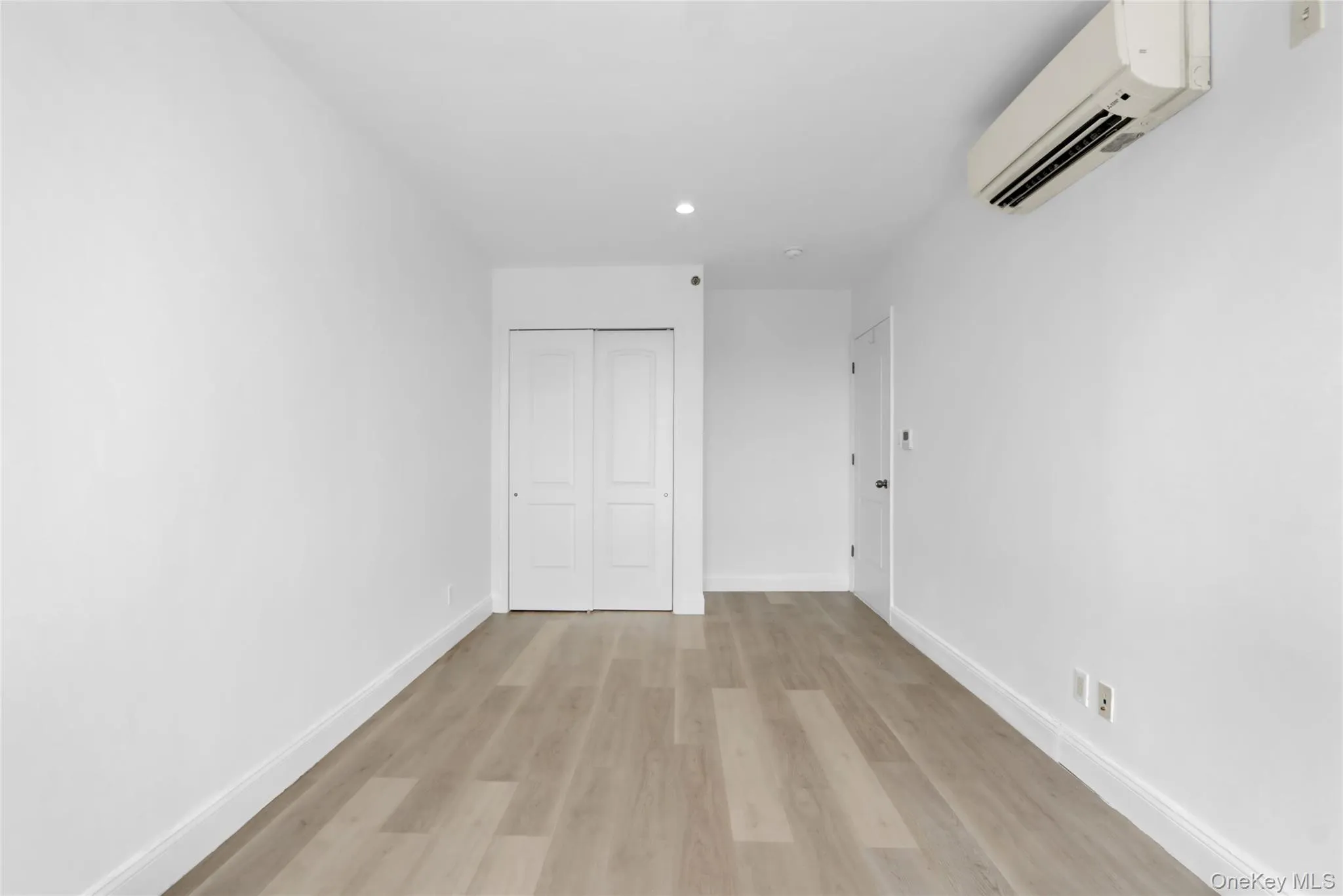 Unfurnished bedroom featuring light wood finished floors, a wall unit AC, a closet, and recessed lighting Unfurnished bedroom featuring light wood finished floors, a wall unit AC, a closet, and recessed lighting