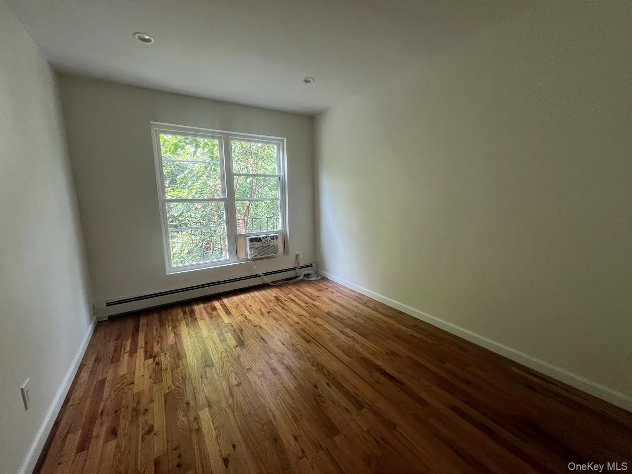 Unfurnished room with a baseboard radiator, wood finished floors, and recessed lighting Unfurnished room with a baseboard radiator, wood finished floors, and recessed lighting