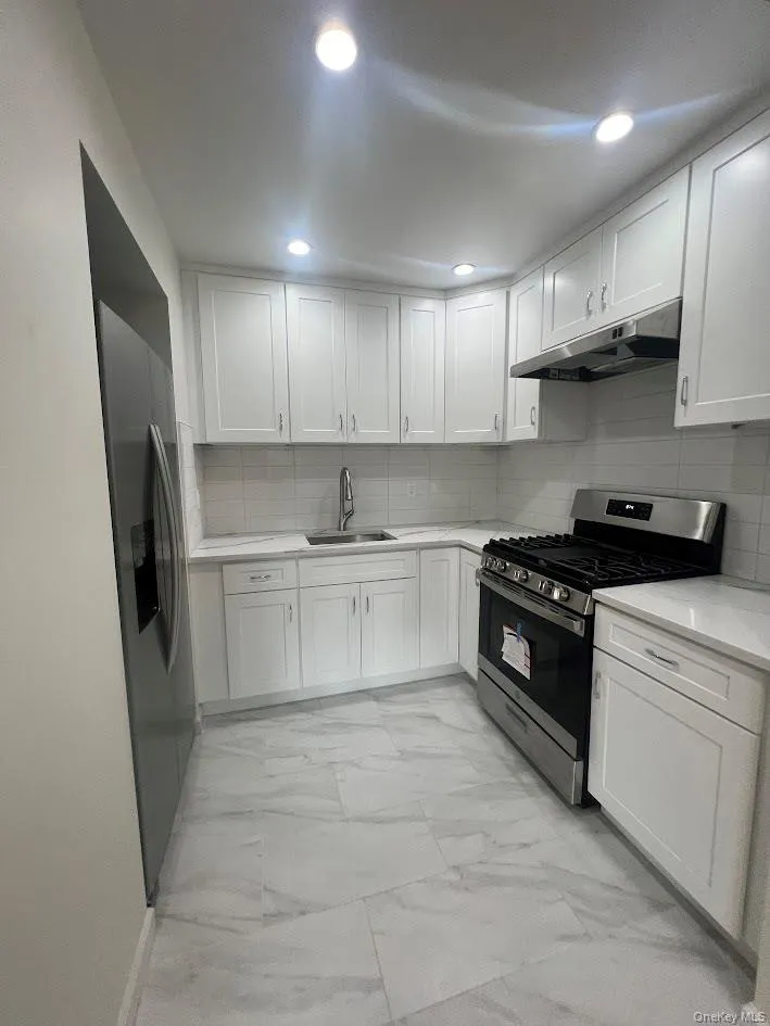 Kitchen with stainless steel appliances, decorative backsplash, white cabinetry, and recessed lighting Kitchen with stainless steel appliances, decorative backsplash, white cabinetry, and recessed lighting
