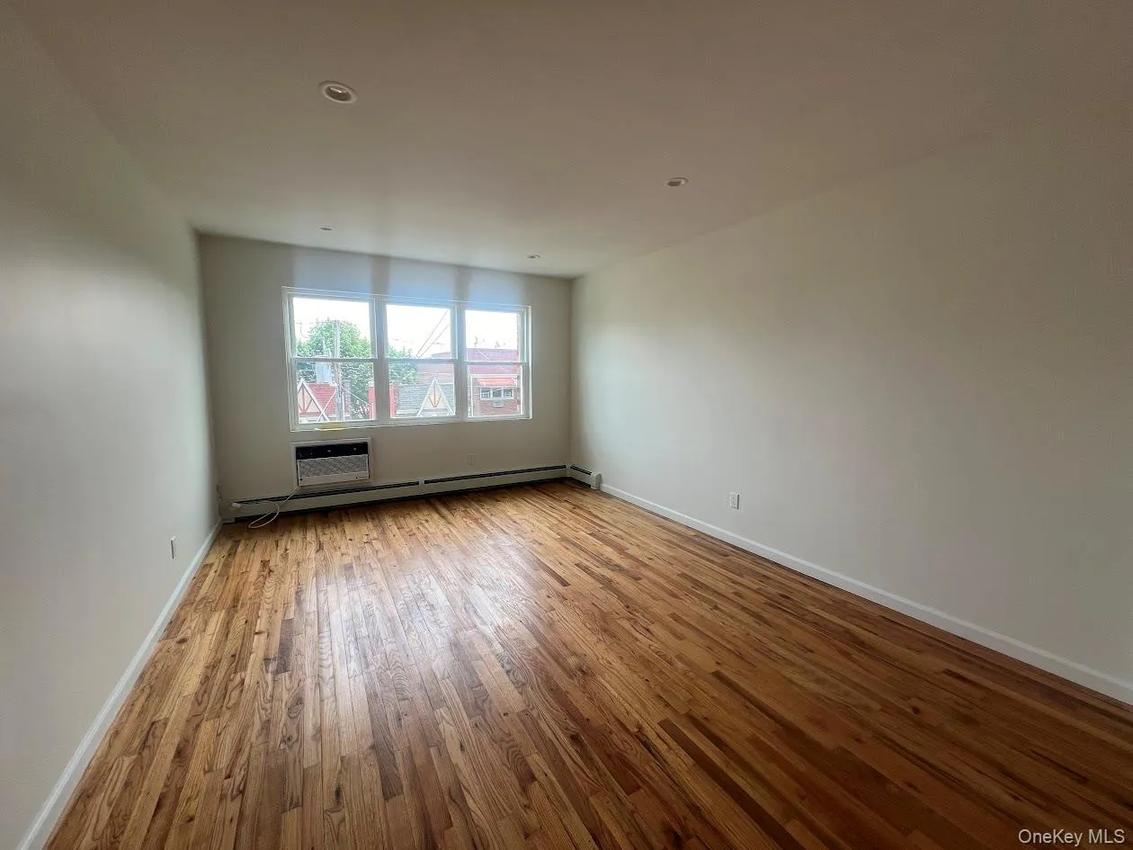 Spare room featuring light wood-style flooring, a baseboard radiator, a wall mounted air conditioner, and recessed lighting Spare room featuring light wood-style flooring, a baseboard radiator, a wall mounted air conditioner, and recessed lighting
