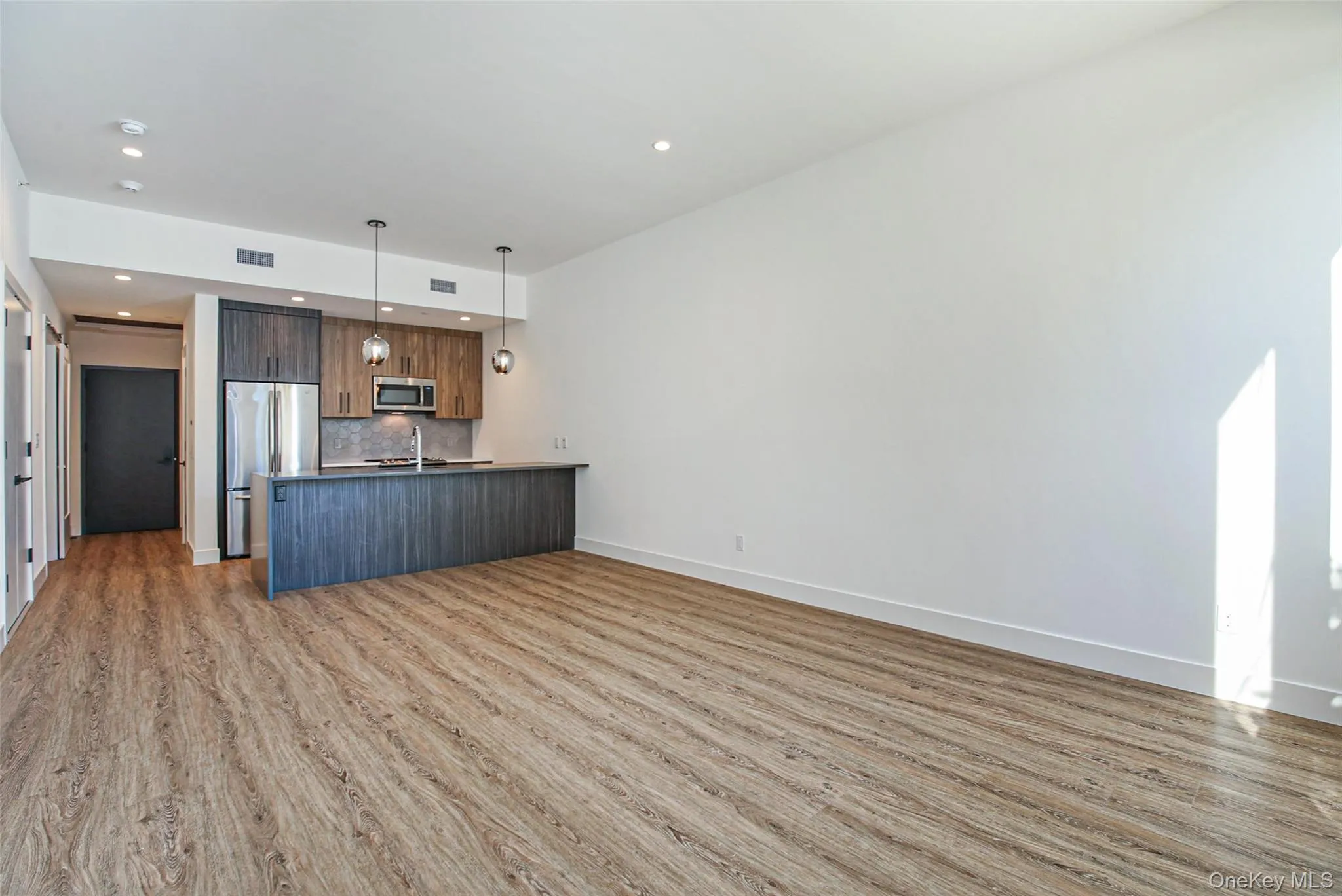 Unfurnished living room with light wood-style floors and recessed lighting Unfurnished living room with light wood-style floors and recessed lighting