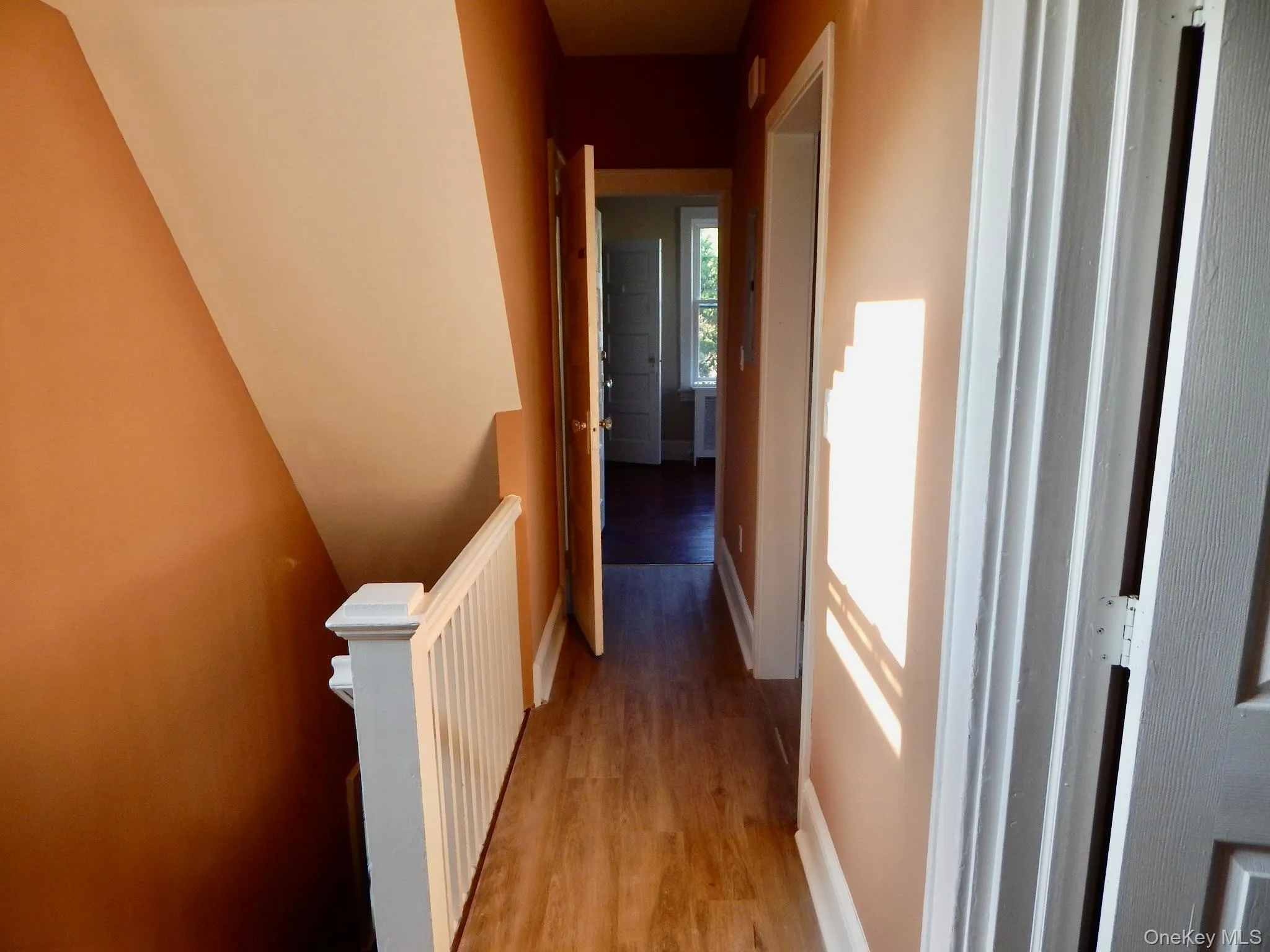 Hall featuring light wood finished floors and an upstairs landing Hall featuring light wood finished floors and an upstairs landing