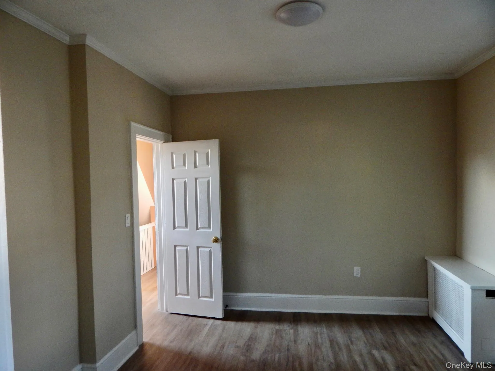 Empty room with radiator, dark wood-type flooring, and ornamental molding Empty room with radiator, dark wood-type flooring, and ornamental molding