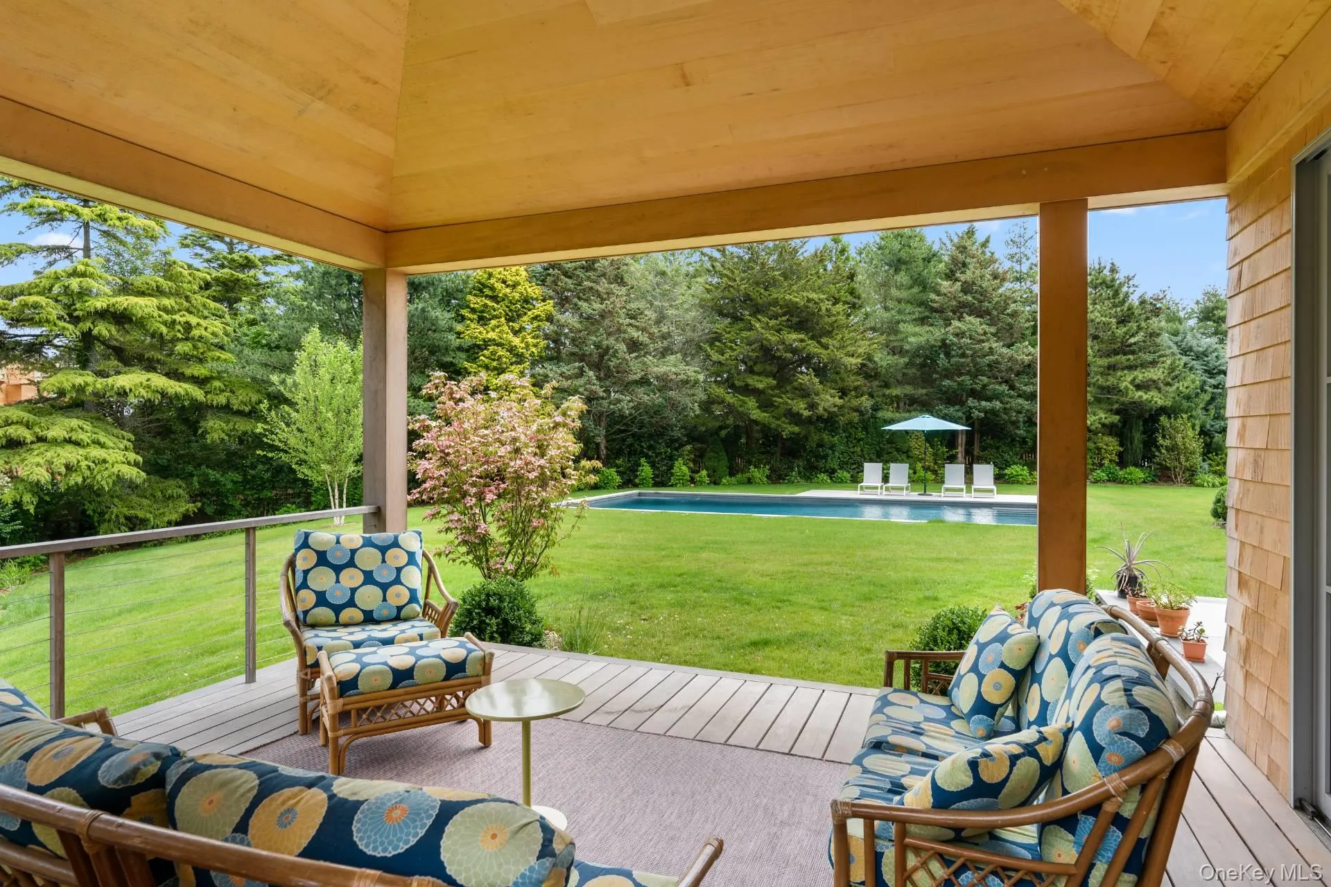 View of patio featuring a wooden deck, view of scattered trees, and an outdoor pool View of patio featuring a wooden deck, view of scattered trees, and an outdoor pool