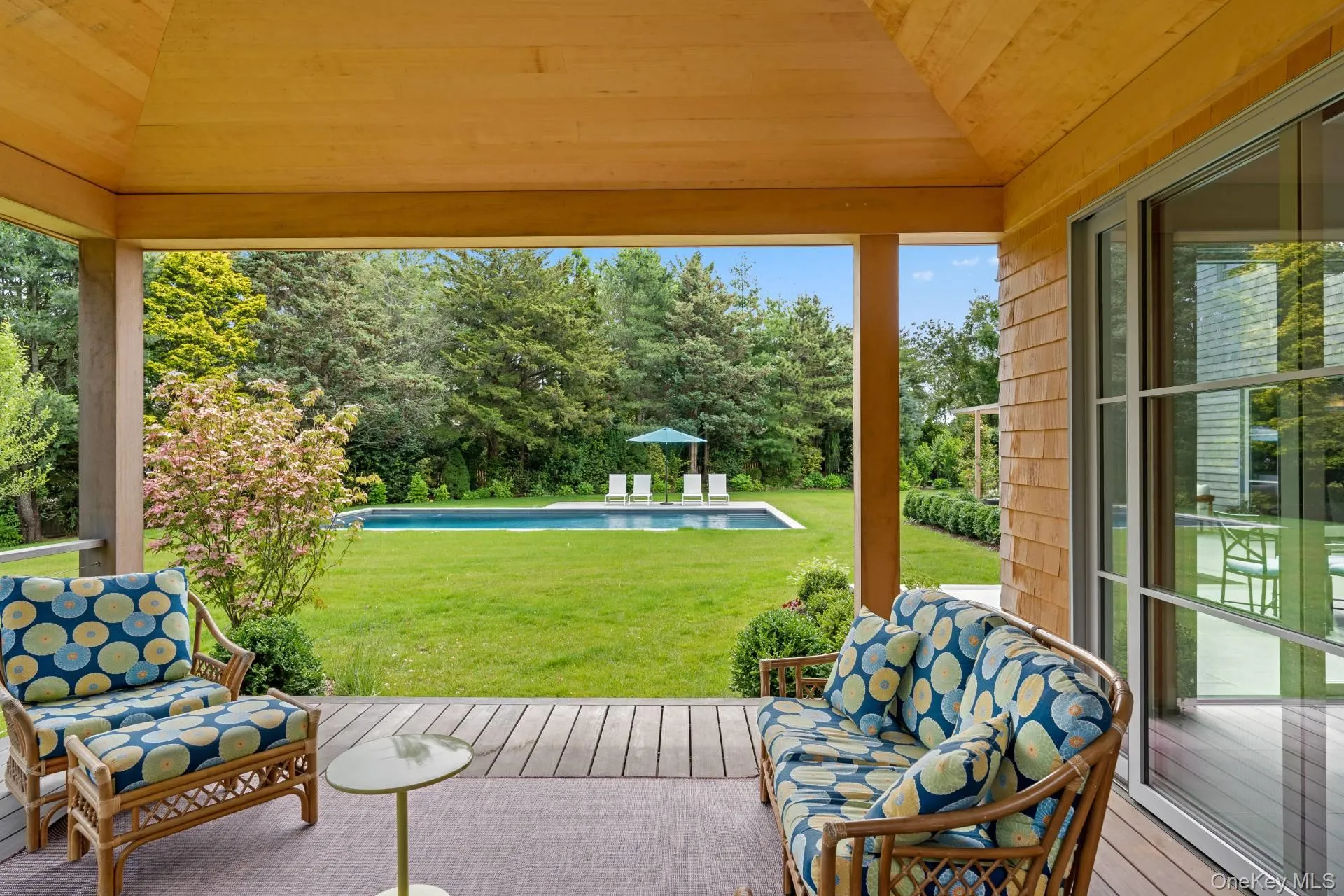 View of patio / terrace featuring a wooden deck, view of wooded area, and an outdoor pool View of patio / terrace featuring a wooden deck, view of wooded area, and an outdoor pool