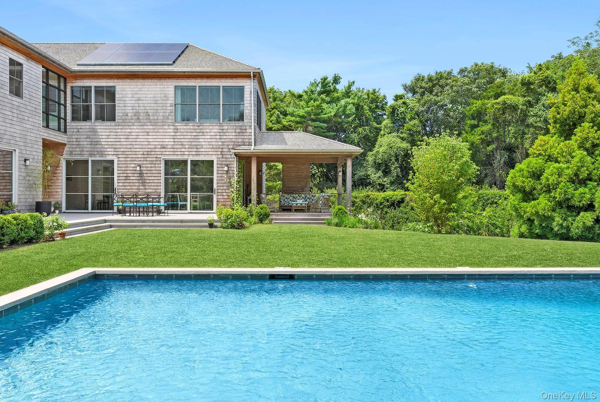Rear view of property featuring solar panels, an outdoor pool, a yard, and a patio area Rear view of property featuring solar panels, an outdoor pool, a yard, and a patio area