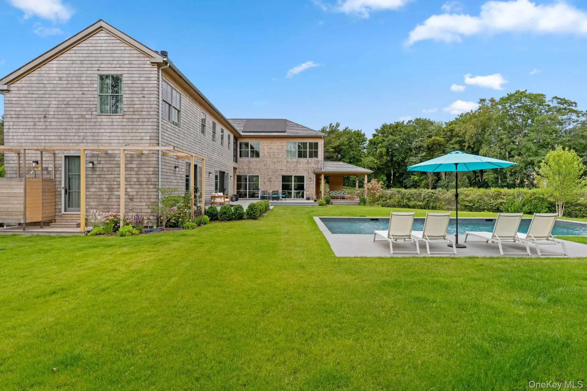 Back of house featuring a patio, roof mounted solar panels, a yard, and an outdoor pool Back of house featuring a patio, roof mounted solar panels, a yard, and an outdoor pool