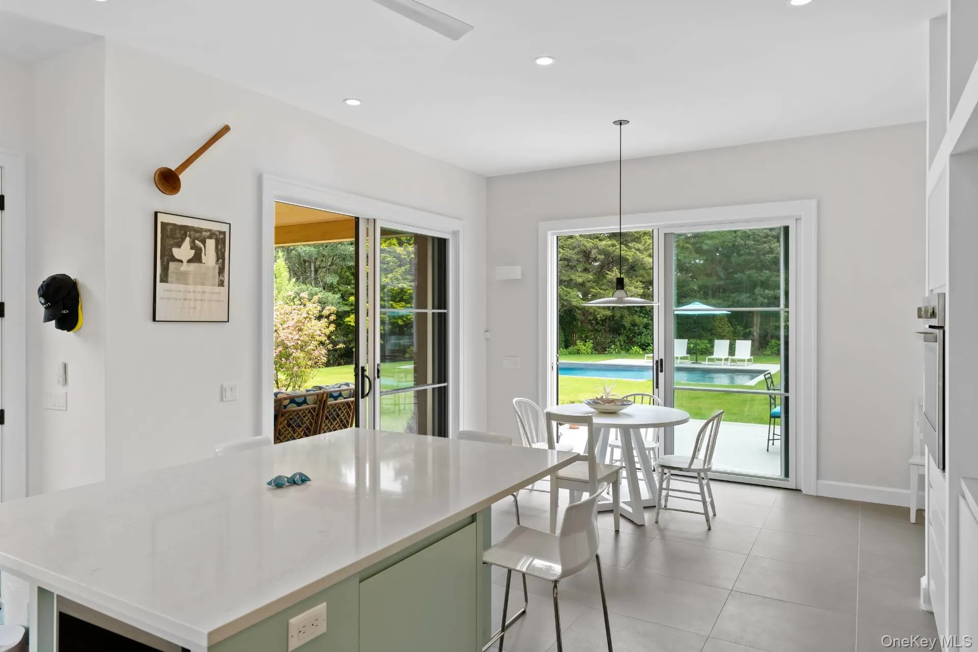 Kitchen featuring decorative light fixtures, recessed lighting, light stone countertops, green cabinetry, and a breakfast bar area Kitchen featuring decorative light fixtures, recessed lighting, light stone countertops, green cabinetry, and a breakfast bar area