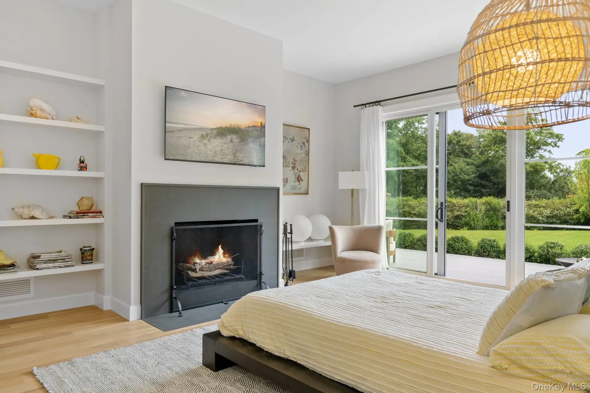 Bedroom with light wood-style flooring, a chandelier, a warm lit fireplace, and access to outside Bedroom with light wood-style flooring, a chandelier, a warm lit fireplace, and access to outside