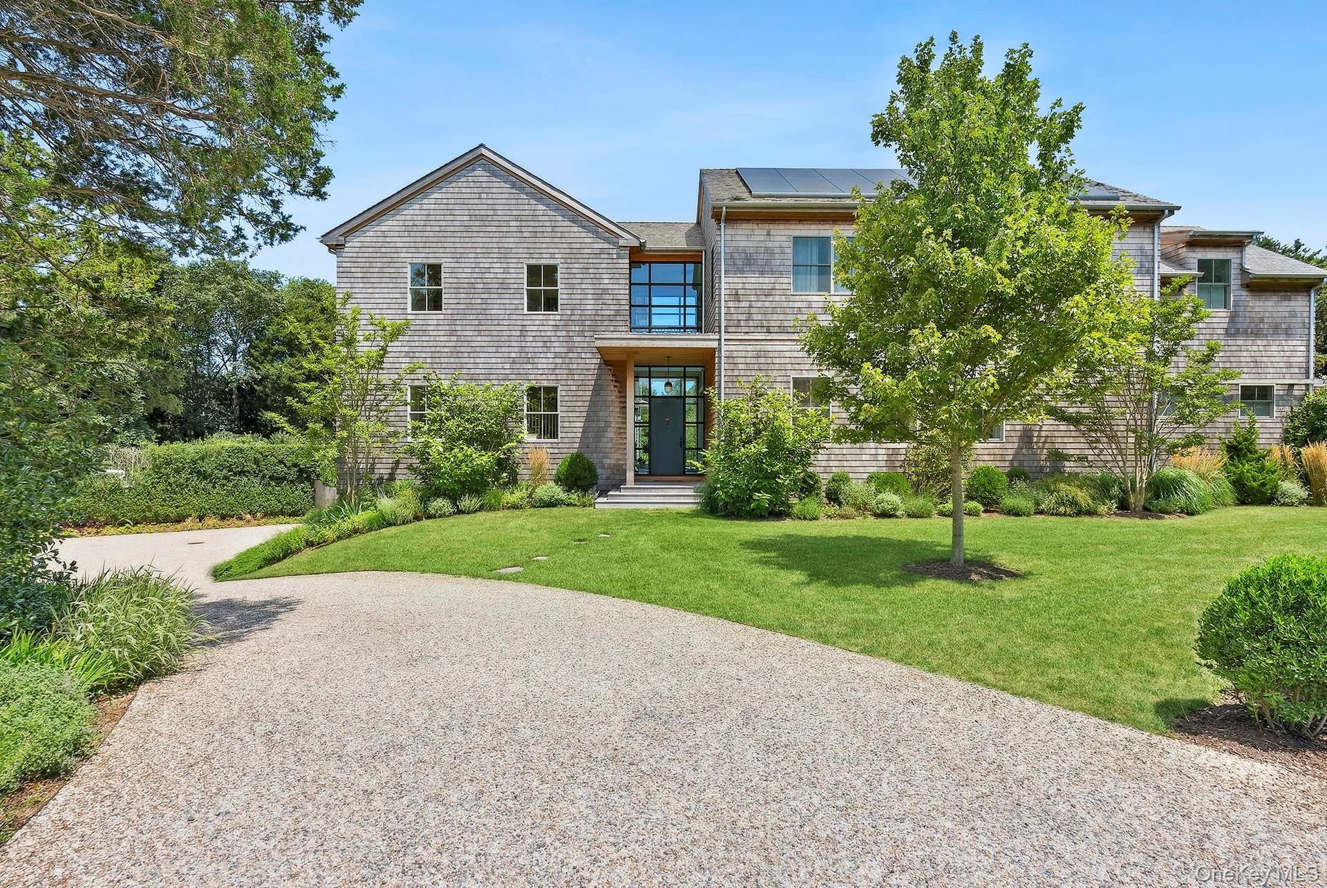 View of front facade with a front lawn, solar panels, and driveway View of front facade with a front lawn, solar panels, and driveway