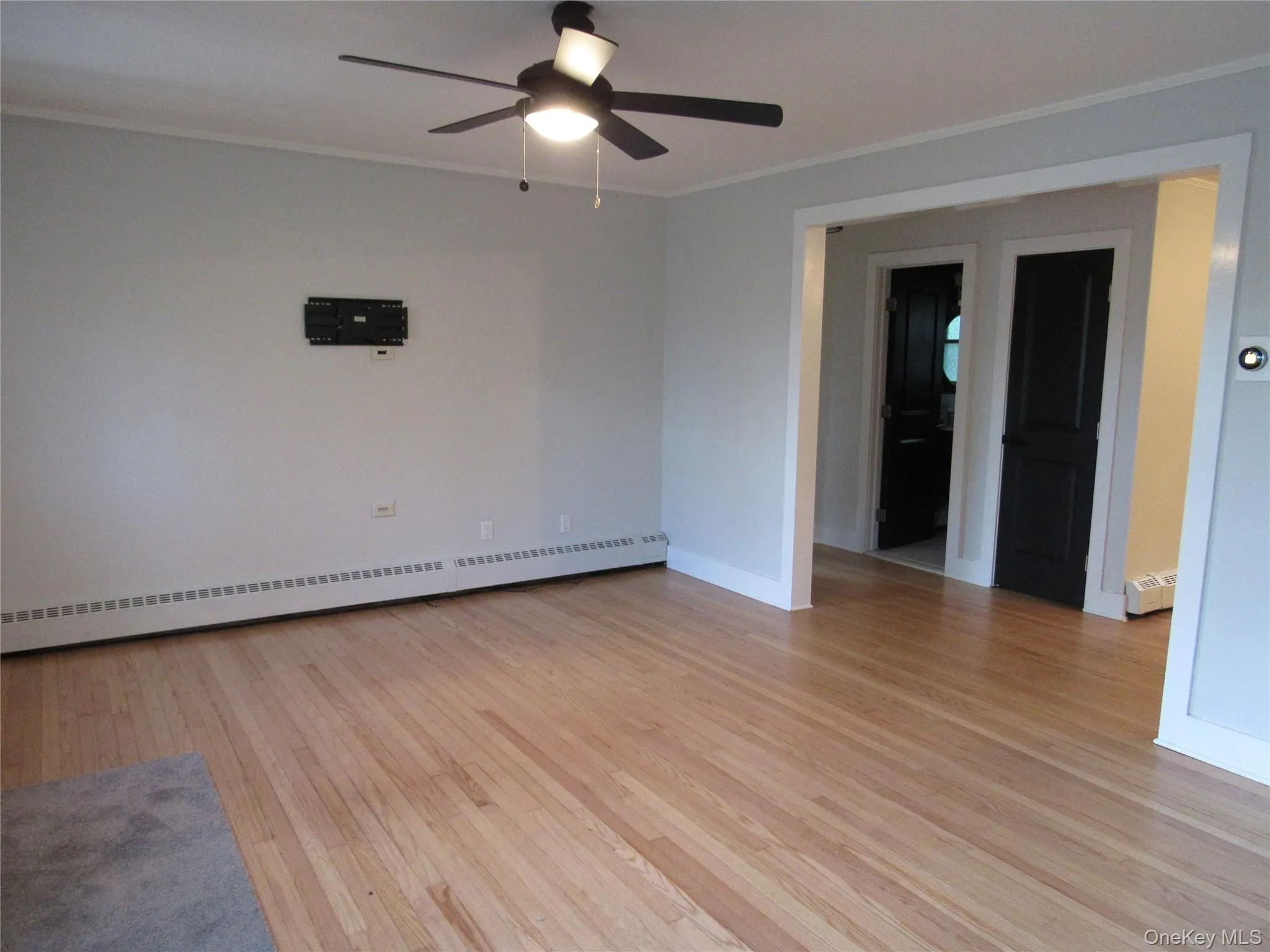 Empty room featuring crown molding, light wood-style flooring, baseboard heating, and ceiling fan Empty room featuring crown molding, light wood-style flooring, baseboard heating, and ceiling fan
