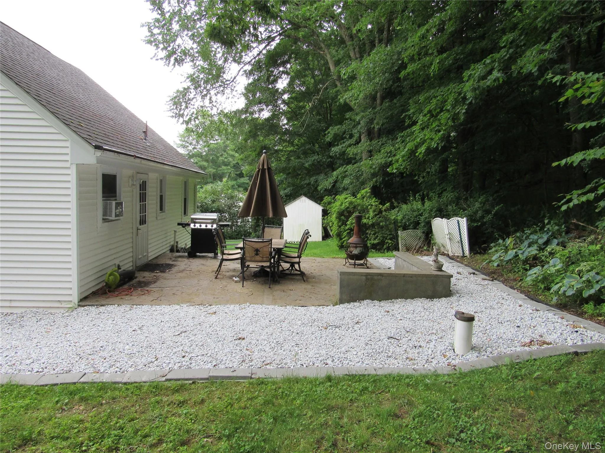 View of patio featuring outdoor dining area, area for grilling, and view of wooded area View of patio featuring outdoor dining area, area for grilling, and view of wooded area