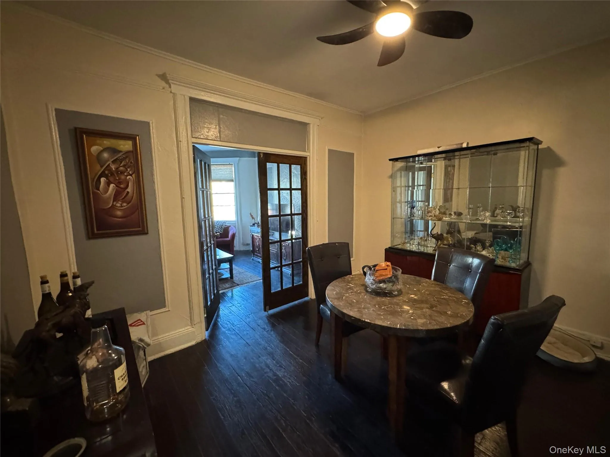 Dining area with dark wood-style flooring, ornamental molding, ceiling fan, and french doors Dining area with dark wood-style flooring, ornamental molding, ceiling fan, and french doors
