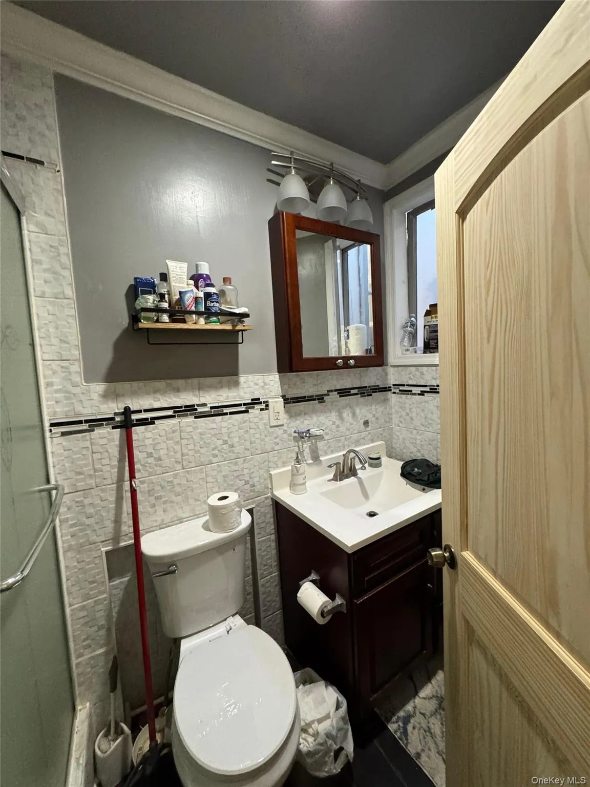 Bathroom with vanity, tile walls, a shower stall, crown molding, and a wainscoted wall Bathroom with vanity, tile walls, a shower stall, crown molding, and a wainscoted wall