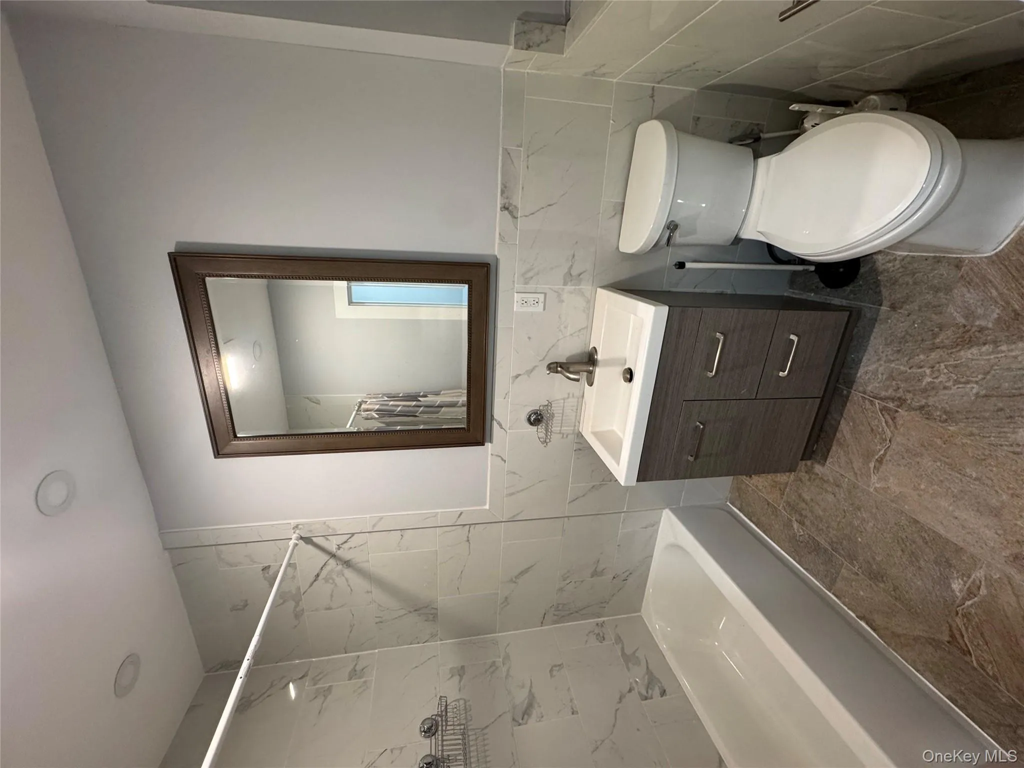 Bathroom with tile walls, vanity, shower / tub combo with curtain, and a wainscoted wall Bathroom with tile walls, vanity, shower / tub combo with curtain, and a wainscoted wall