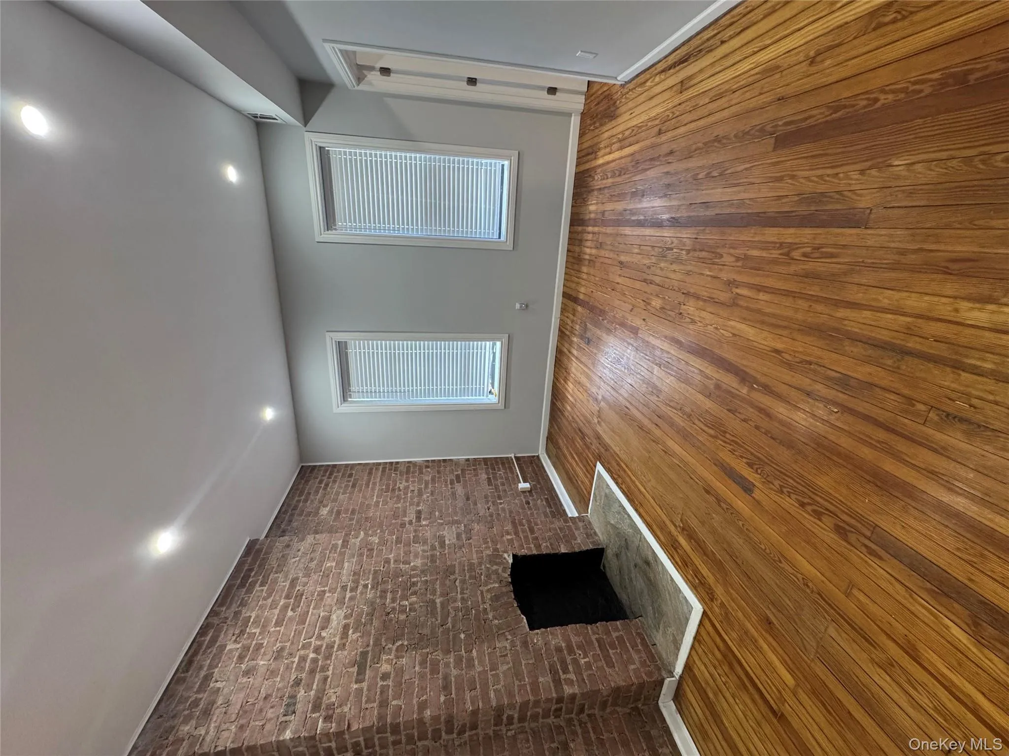Unfurnished living room featuring brick wall, a brick fireplace, hardwood / wood-style floors, and recessed lighting Unfurnished living room featuring brick wall, a brick fireplace, hardwood / wood-style floors, and recessed lighting