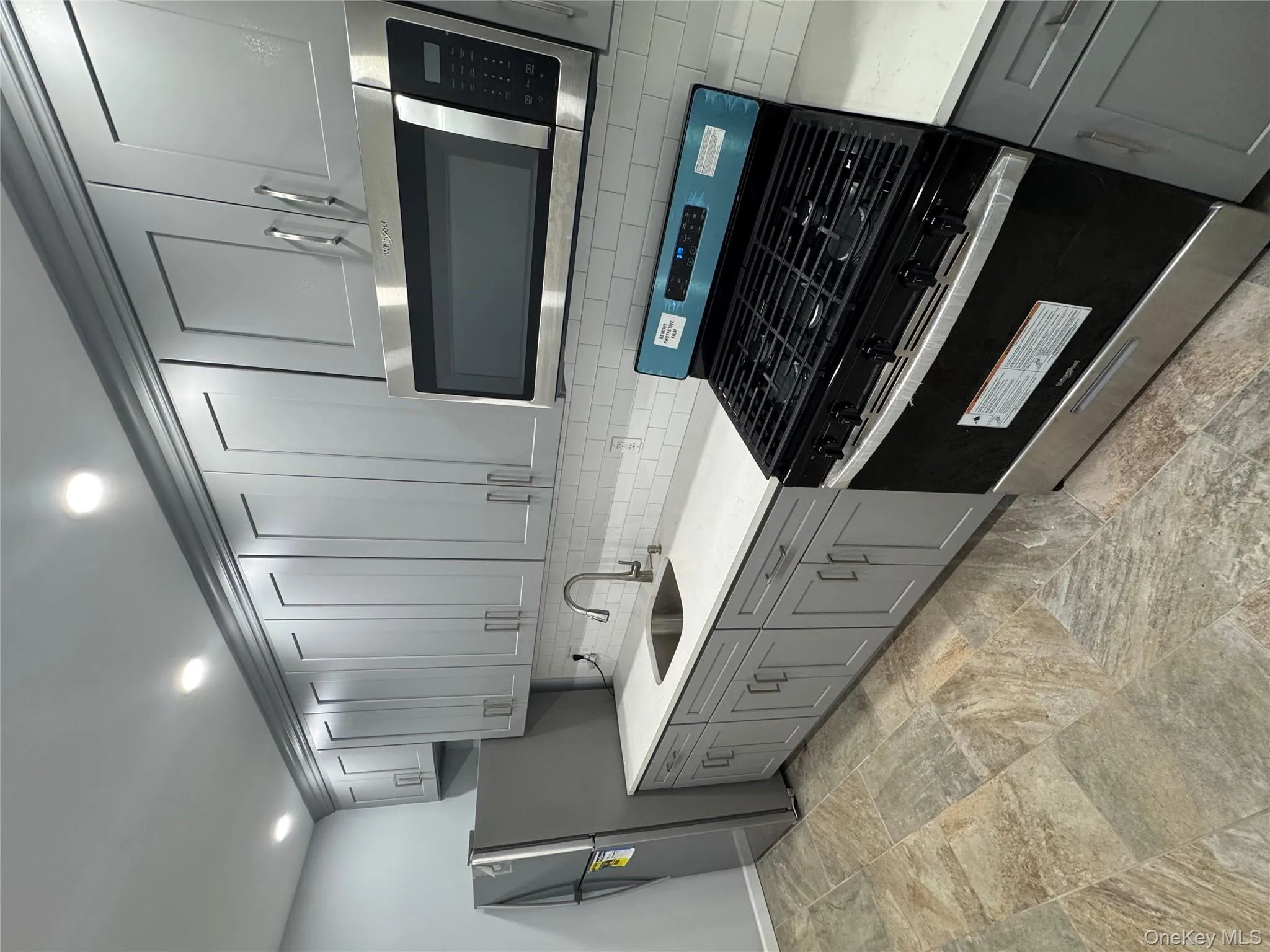 Kitchen with gray cabinetry, range, stainless steel microwave, light stone countertops, and recessed lighting Kitchen with gray cabinetry, range, stainless steel microwave, light stone countertops, and recessed lighting