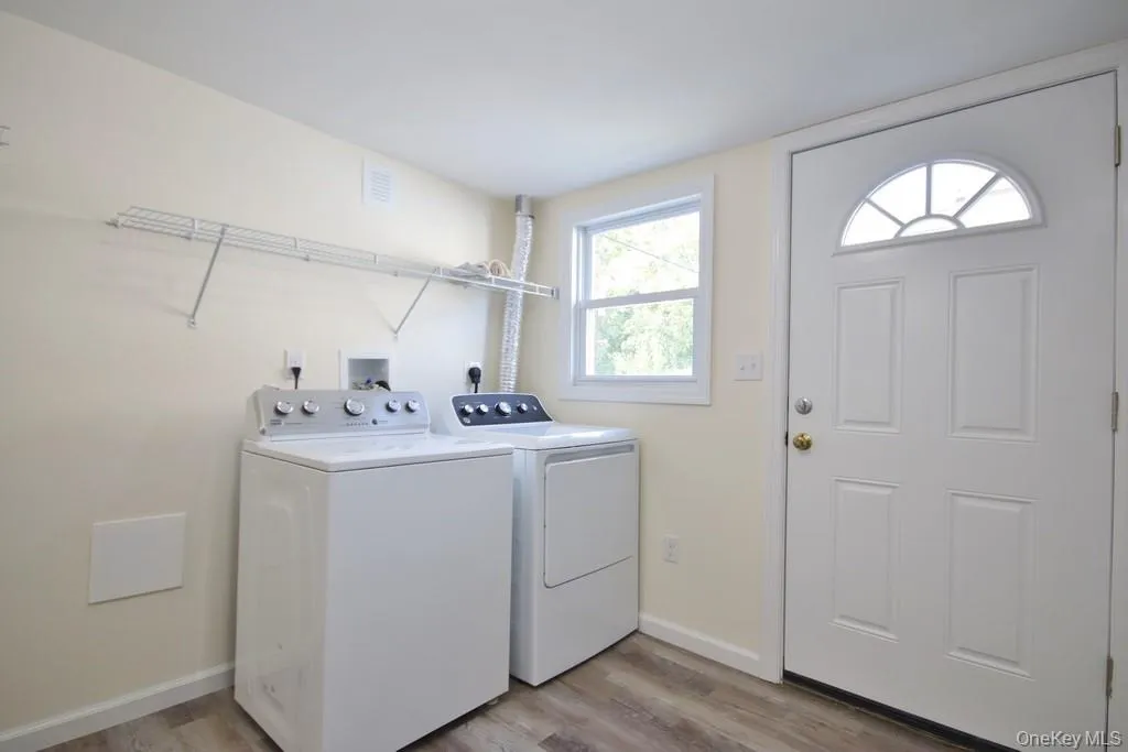 Laundry area with light wood-style flooring and washing machine and dryer Laundry area with light wood-style flooring and washing machine and dryer