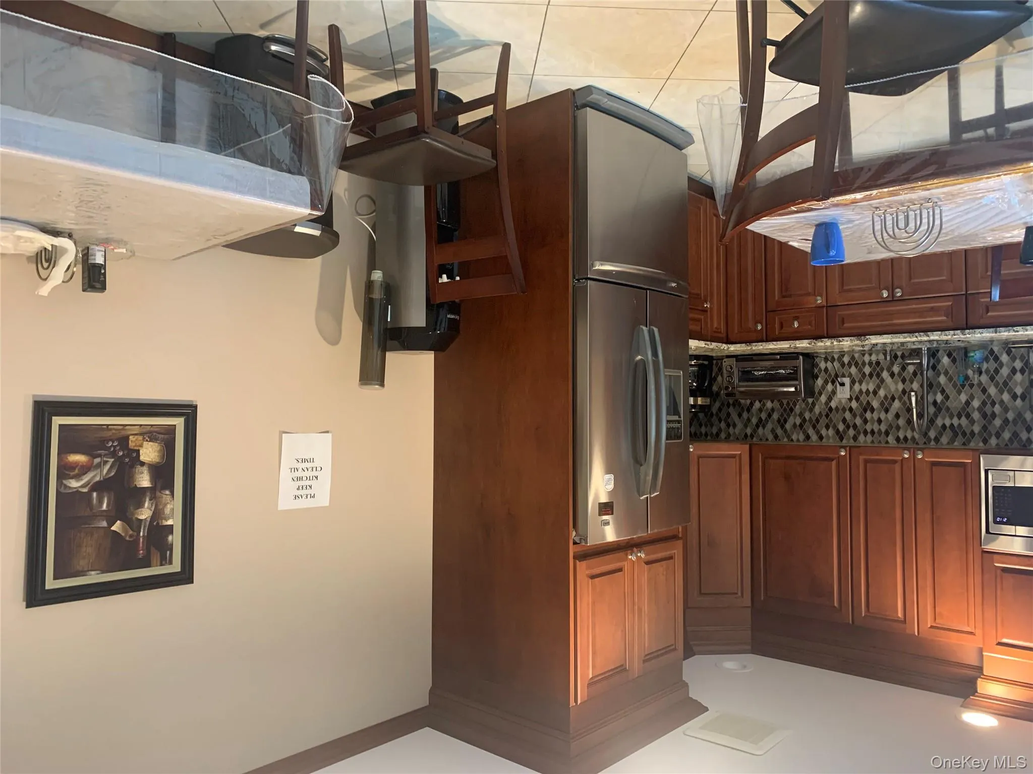 Kitchen with refrigerator, light stone counters, decorative backsplash, light tile patterned flooring, and white microwave Kitchen with refrigerator, light stone counters, decorative backsplash, light tile patterned flooring, and white microwave