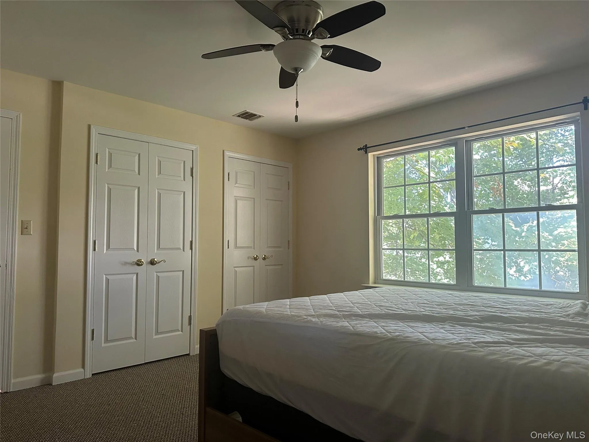 Bedroom featuring two closets, dark colored carpet, and a ceiling fan Bedroom featuring two closets, dark colored carpet, and a ceiling fan