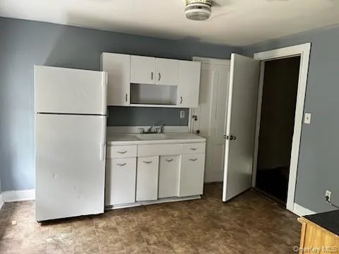 Kitchen with tile patterned floors, sink, white cabinets, and white refrigerator Kitchen with tile patterned floors, sink, white cabinets, and white refrigerator