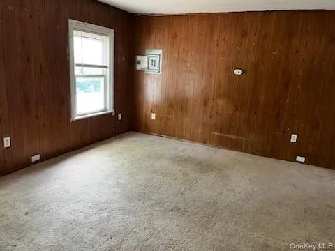 Unfurnished room featuring carpet floors and wooden walls Unfurnished room featuring carpet floors and wooden walls
