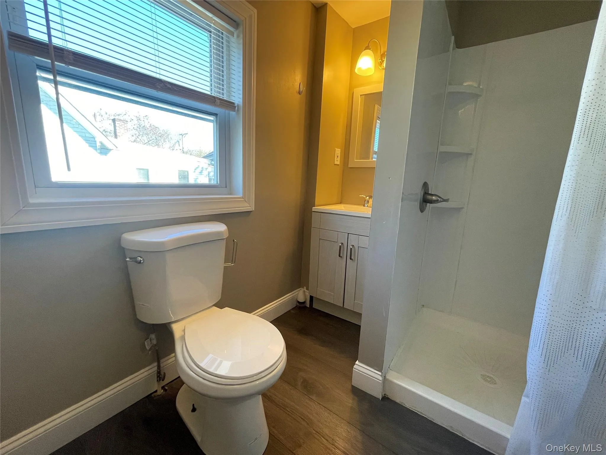 Full bathroom featuring a stall shower, vanity, and dark wood-type flooring Full bathroom featuring a stall shower, vanity, and dark wood-type flooring