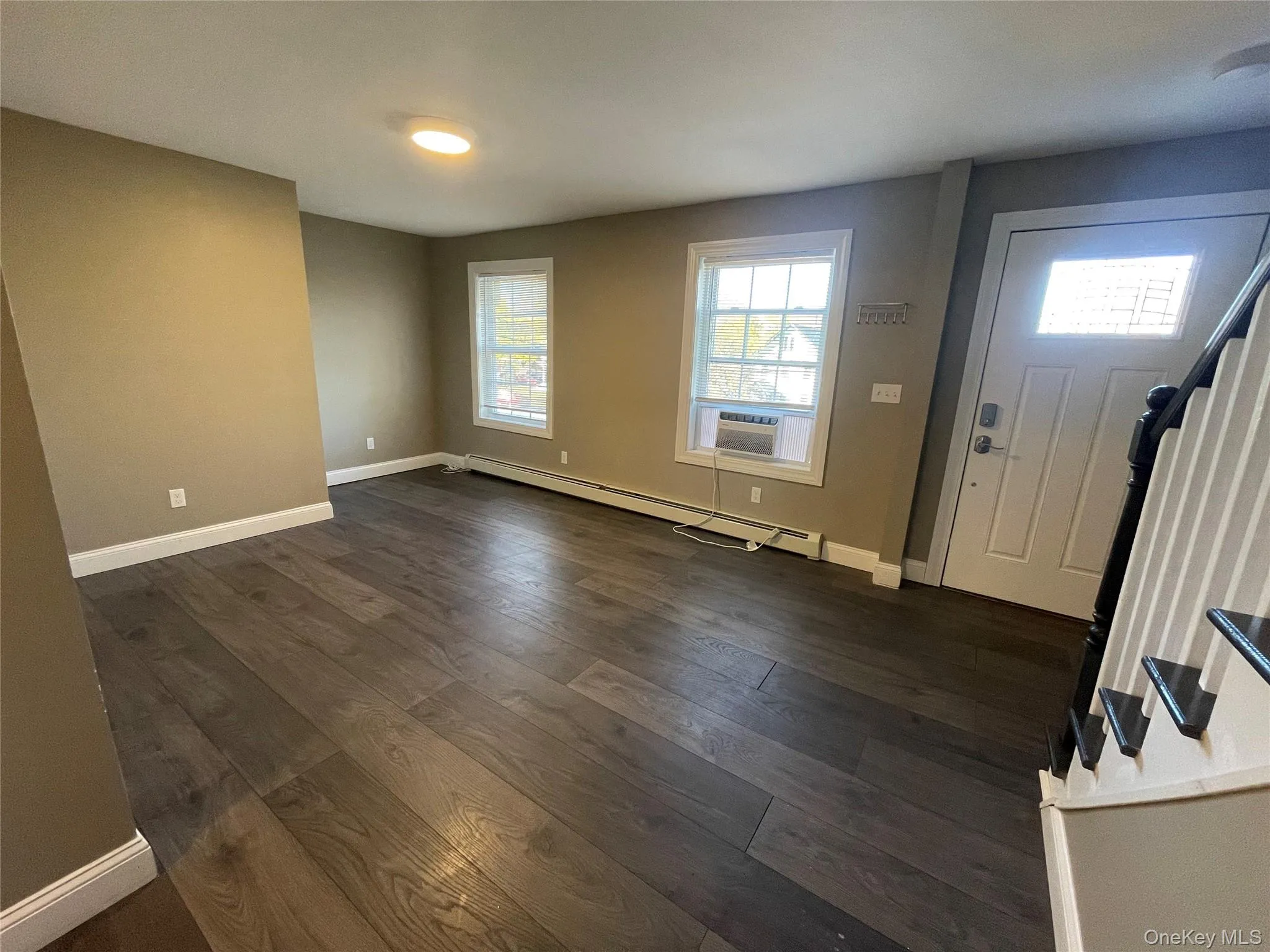 Foyer with baseboard heating, dark wood-type flooring, and stairway Foyer with baseboard heating, dark wood-type flooring, and stairway