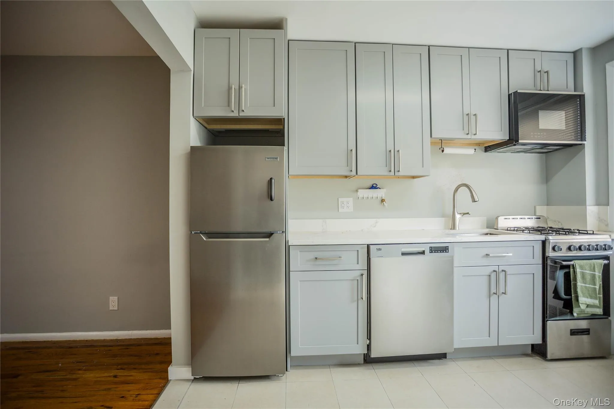 Kitchen with stainless steel appliances, gray cabinetry, and light stone countertops Kitchen with stainless steel appliances, gray cabinetry, and light stone countertops