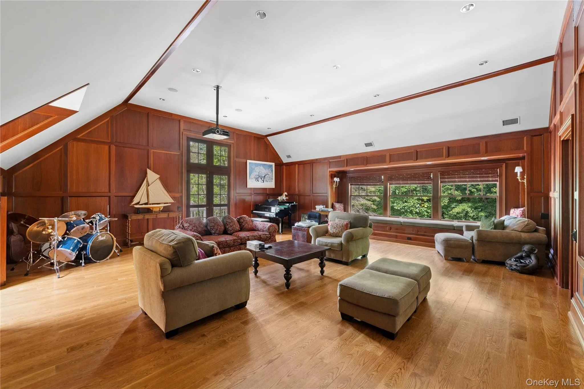 Living area with plenty of natural light, lofted ceiling, wooden walls, light wood-style flooring, and a skylight Living area with plenty of natural light, lofted ceiling, wooden walls, light wood-style flooring, and a skylight