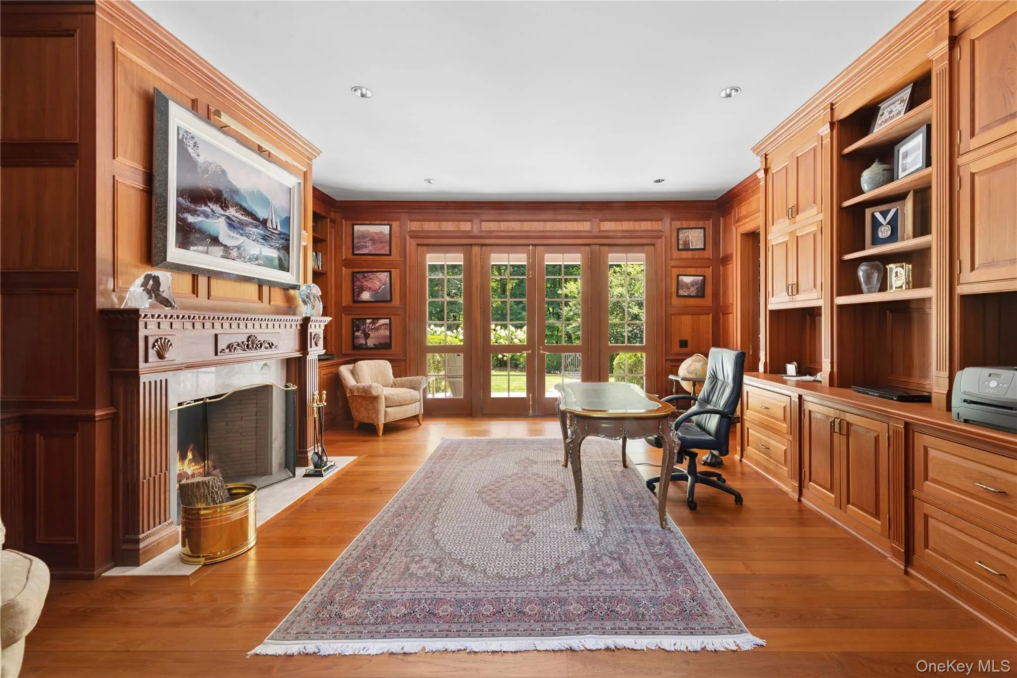 Office space featuring wood walls, built in features, ornamental molding, a high end fireplace, and light wood-style flooring Office space featuring wood walls, built in features, ornamental molding, a high end fireplace, and light wood-style flooring