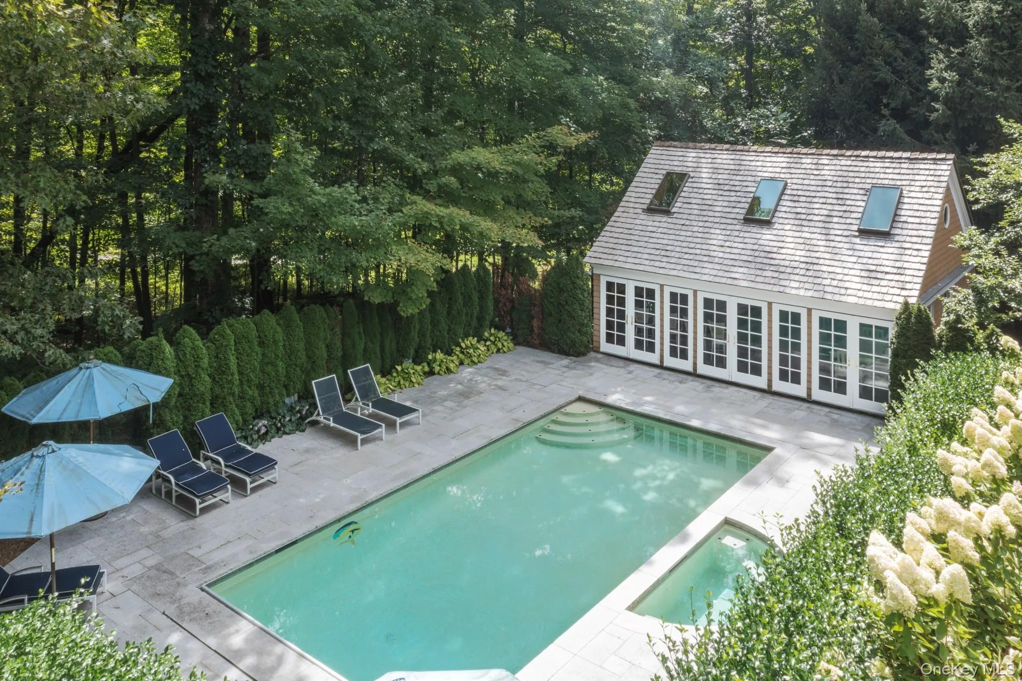 View of swimming pool with a patio area, a pool with connected hot tub, an exterior structure, and an outbuilding View of swimming pool with a patio area, a pool with connected hot tub, an exterior structure, and an outbuilding