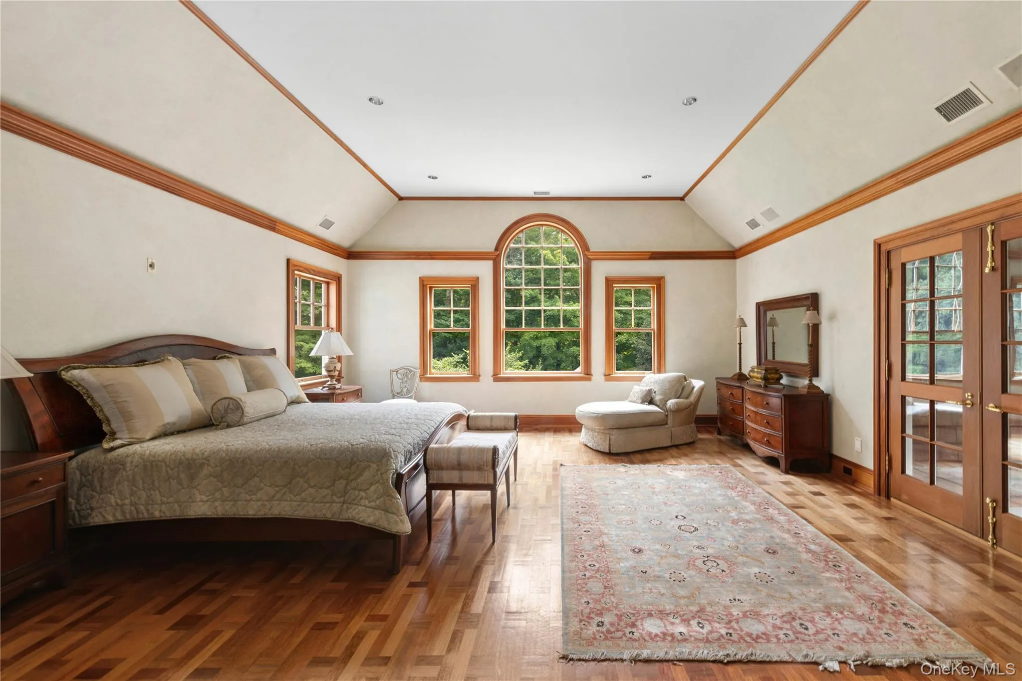 Bedroom featuring lofted ceiling, crown molding, light wood-style flooring, and french doors Bedroom featuring lofted ceiling, crown molding, light wood-style flooring, and french doors