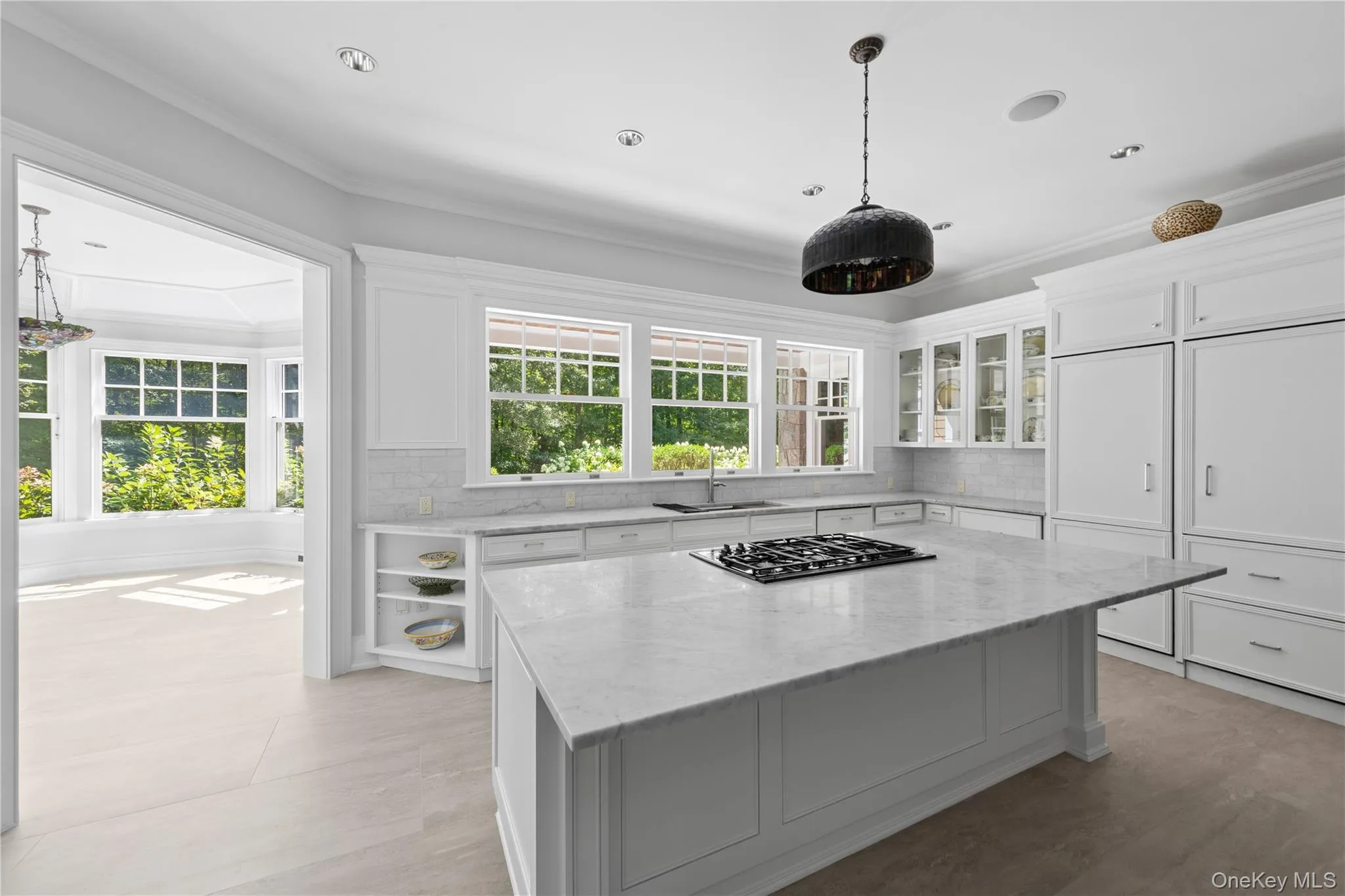 Kitchen featuring decorative backsplash, light stone counters, white cabinets, crown molding, and plenty of natural light Kitchen featuring decorative backsplash, light stone counters, white cabinets, crown molding, and plenty of natural light