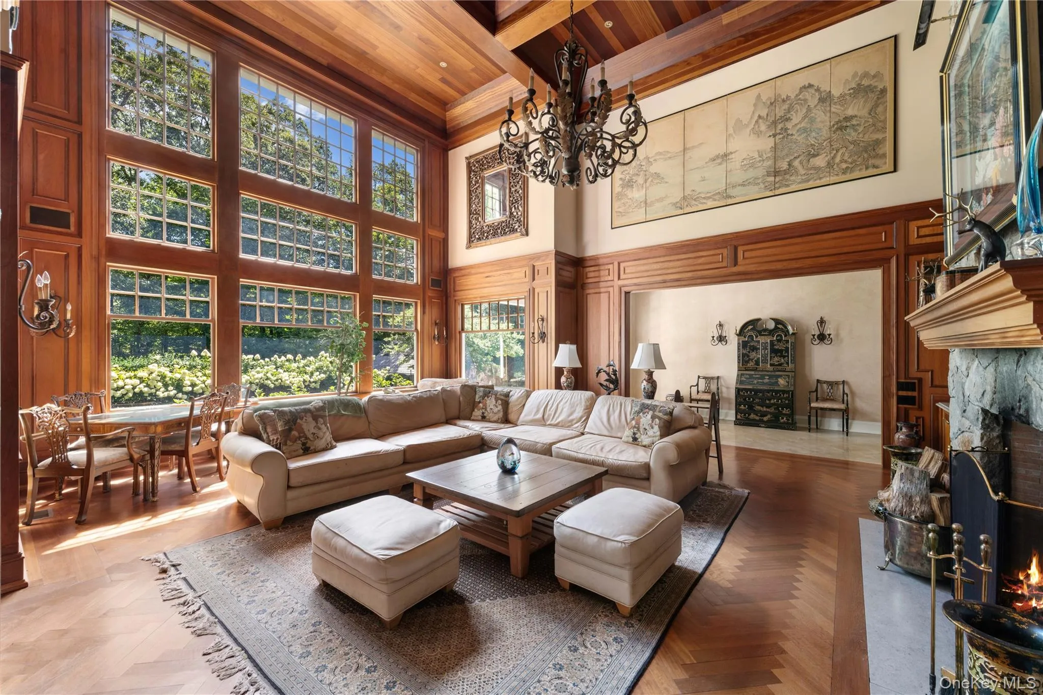 Living room with a fireplace, a wood ceiling with exposed beams, a towering ceiling, and a chandelier Living room with a fireplace, a wood ceiling with exposed beams, a towering ceiling, and a chandelier
