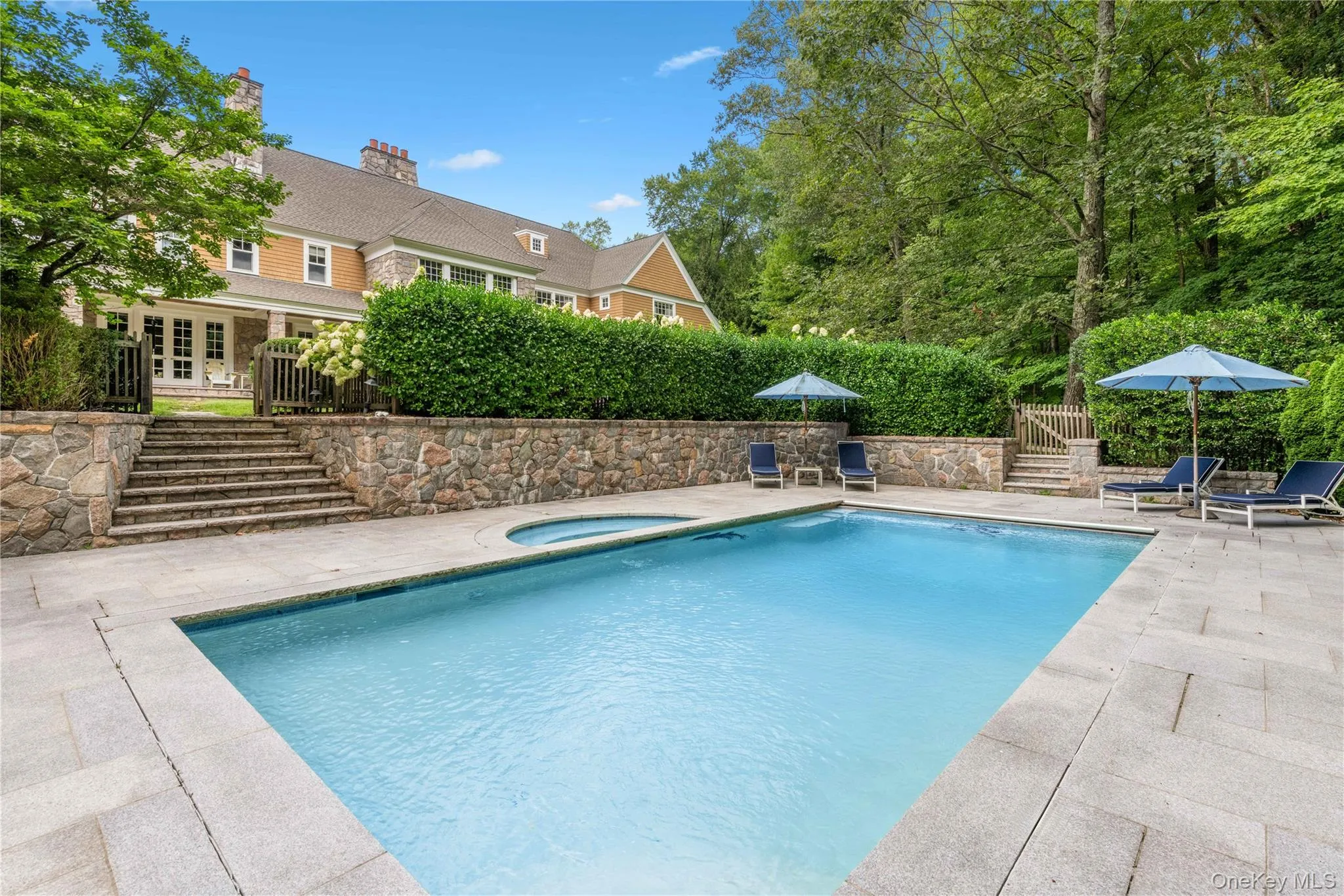 View of pool featuring a patio, stairs, and a pool with connected hot tub View of pool featuring a patio, stairs, and a pool with connected hot tub
