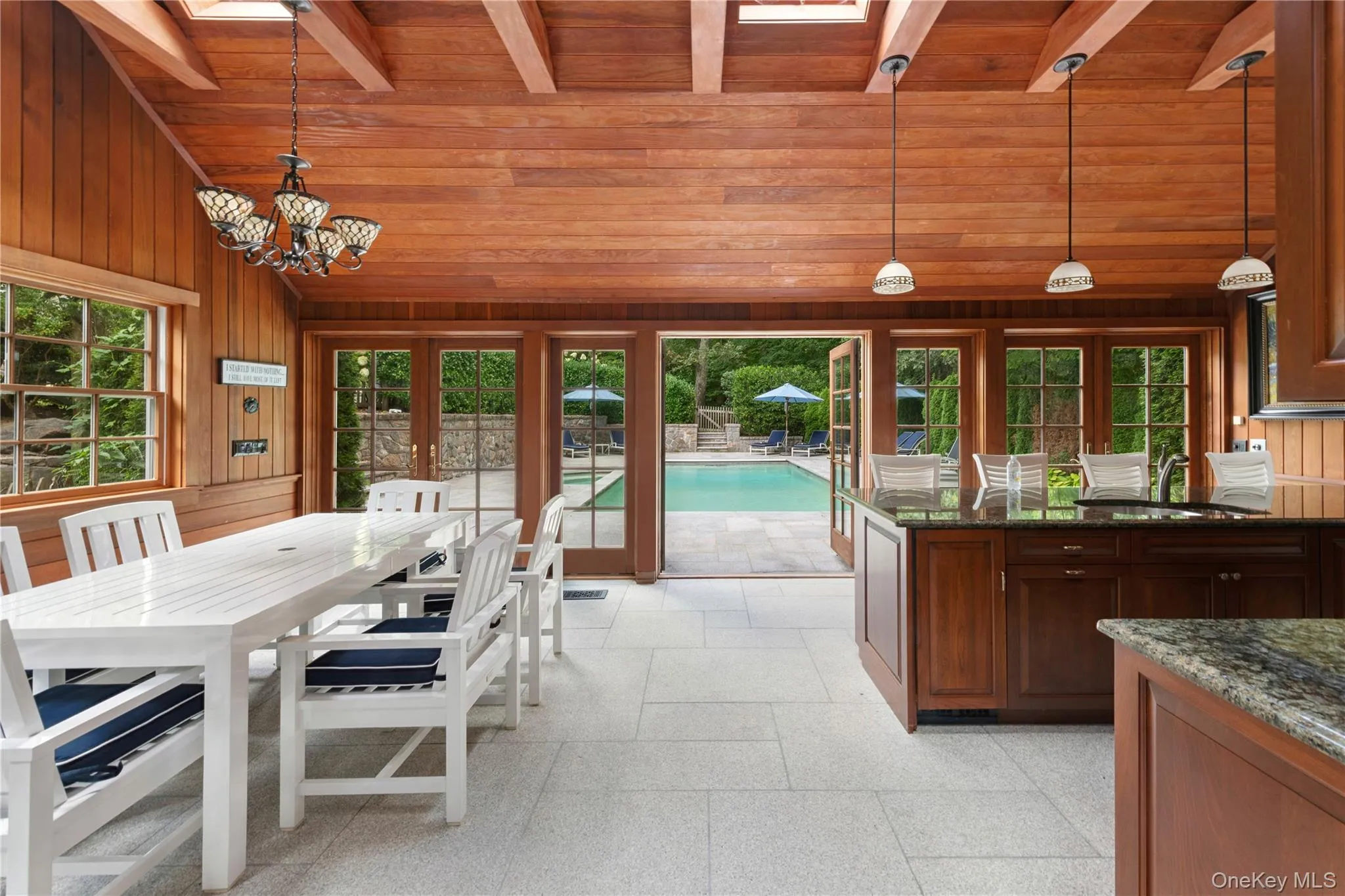 Dining area featuring french doors, a skylight, wooden walls, high vaulted ceiling, and a wood ceiling with exposed beams Dining area featuring french doors, a skylight, wooden walls, high vaulted ceiling, and a wood ceiling with exposed beams